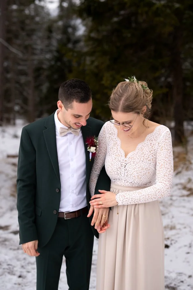 Ein Paar bei einer Winterhochzeit im Freien, die Frau zeigt ihren Ring.