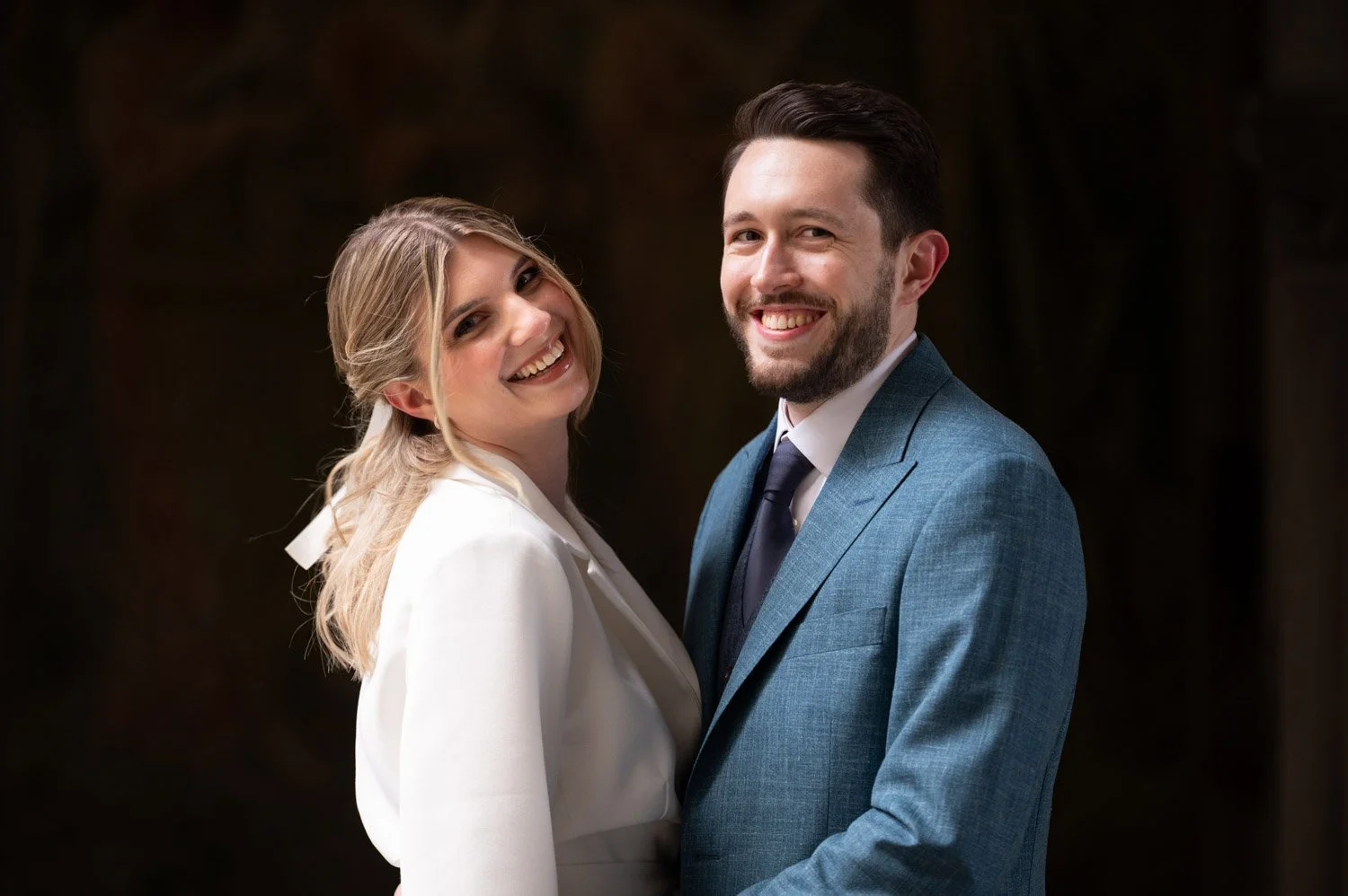 Ein glückliches Paar in formeller Kleidung, das zusammen lächelt.