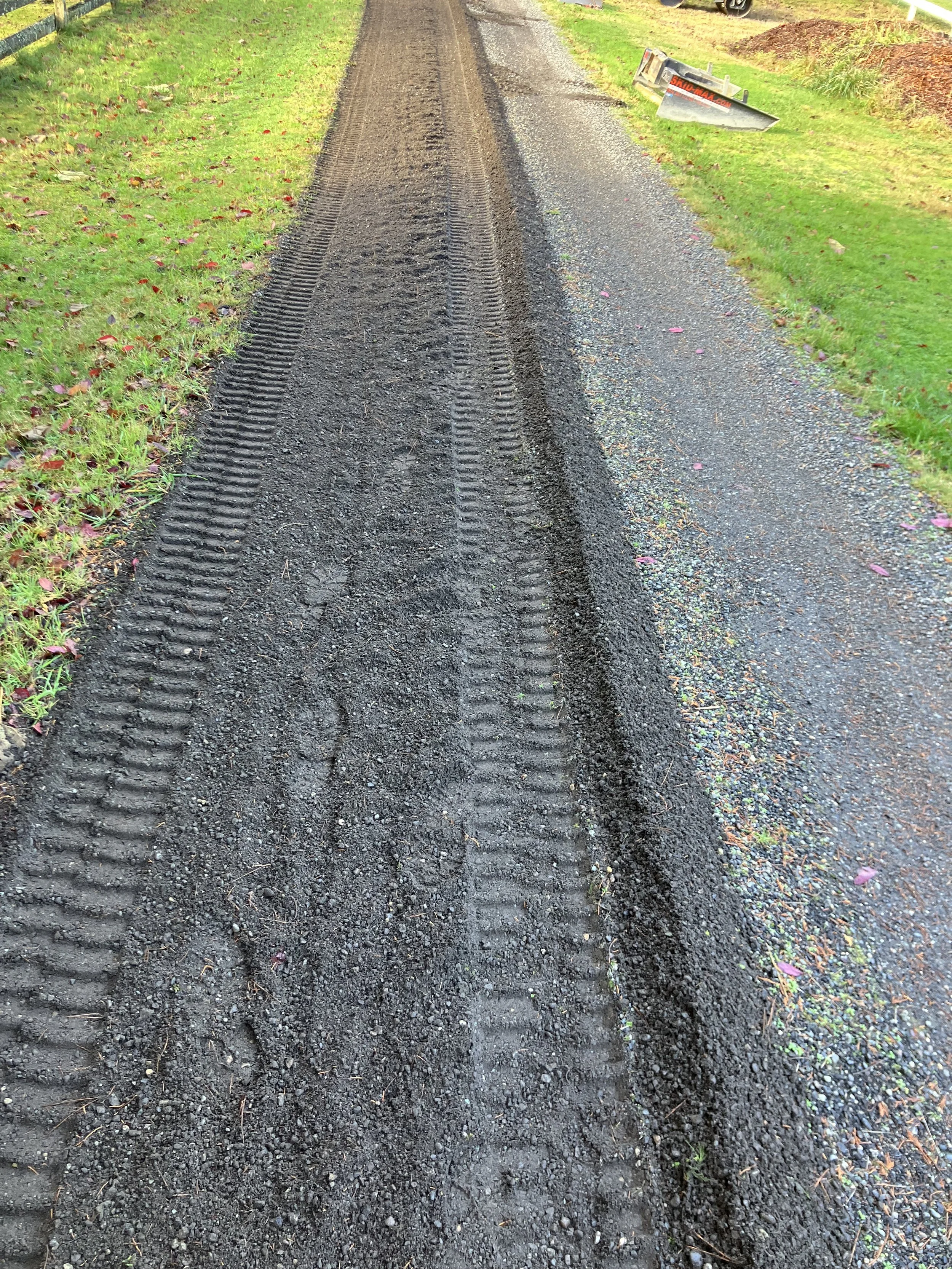 freshly turned over recycled asphalt driveway withe green grass on both sides