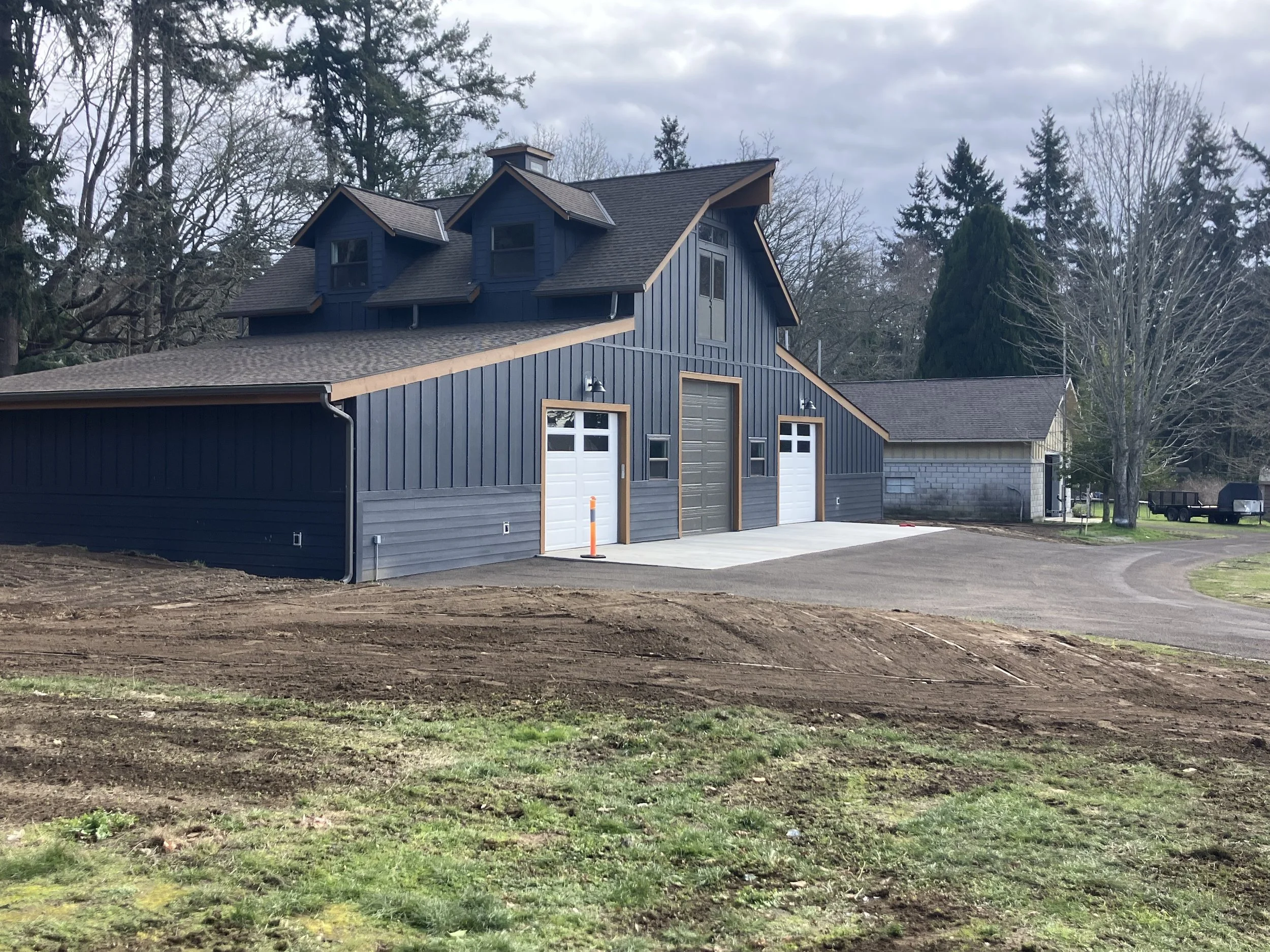 Blue barn with a new recycled asphalt gravel driveway. Resurfaced with a darker color gravel, recycled asphalt