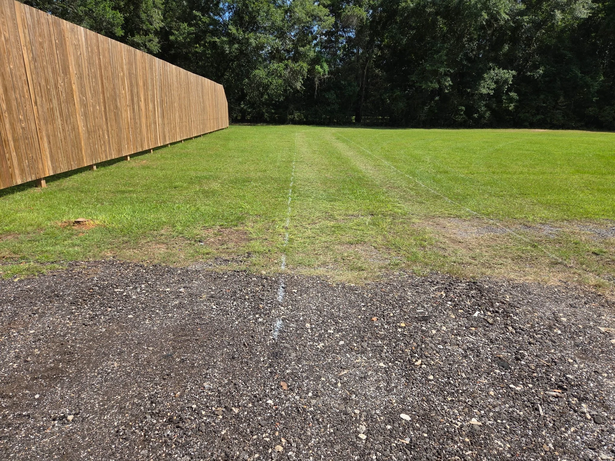 Green grass painted outline for new gravel driveway install