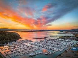 A marina filled with numerous boats during a colorful sunset over a body of water.