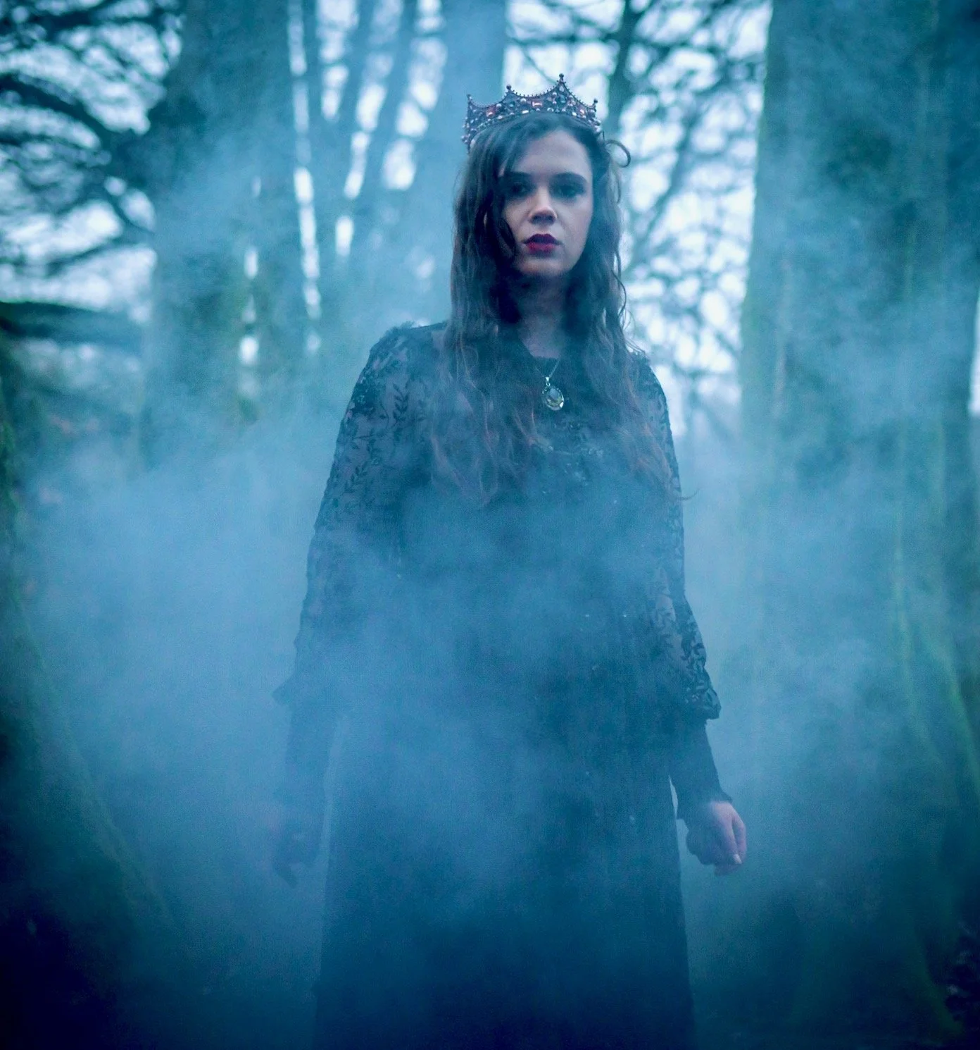 Ria's cover for Favourite Child EP - A woman wearing a crown, black dress, and necklace stands in a foggy outdoor forest setting with bare trees.