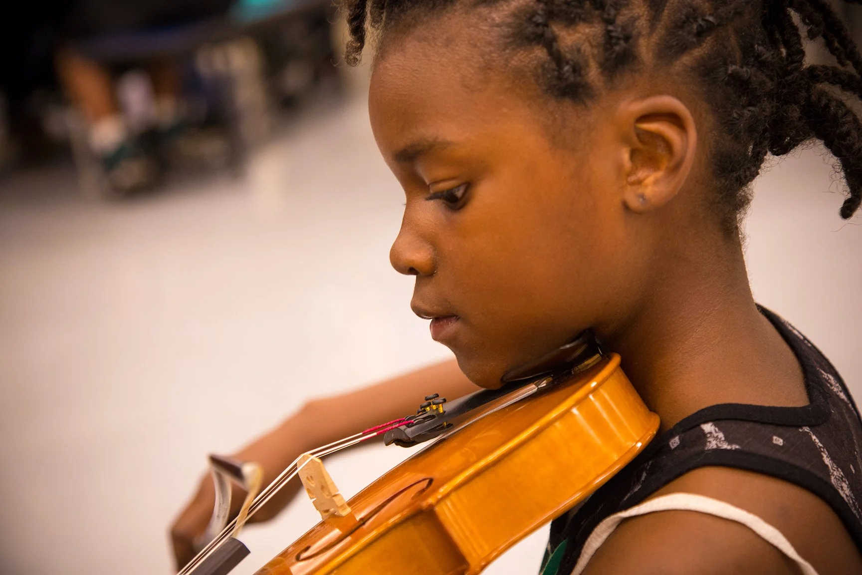 A young girl with braided hair playing a violin.