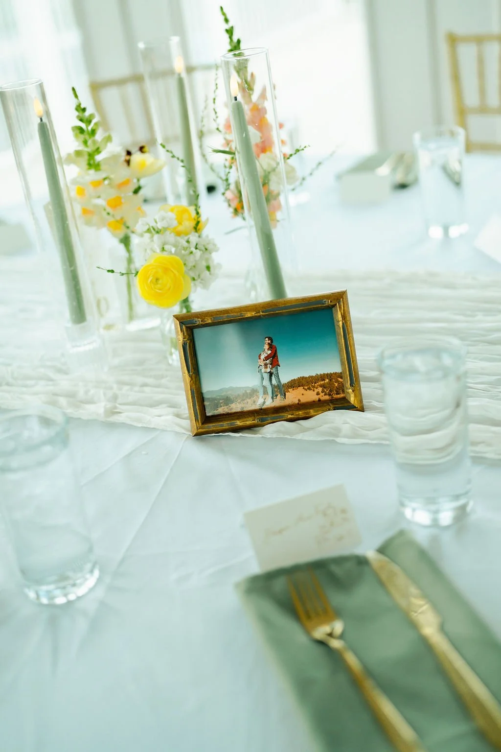 Event table with couple's photo, candles, and bud vases of flowers