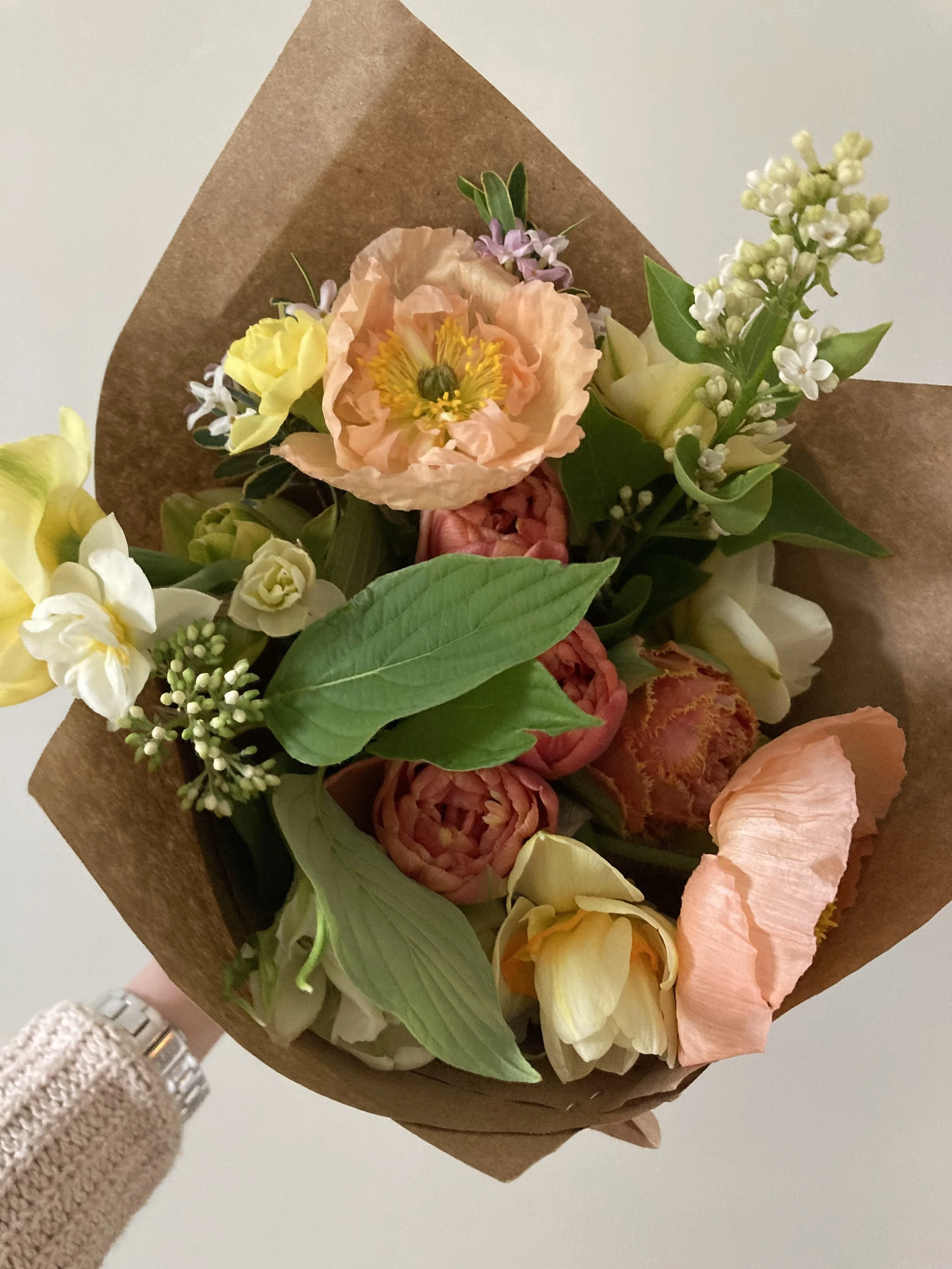 Wrapped flower bouquet with iceland poppies, tulips, narcissus, and viburnum
