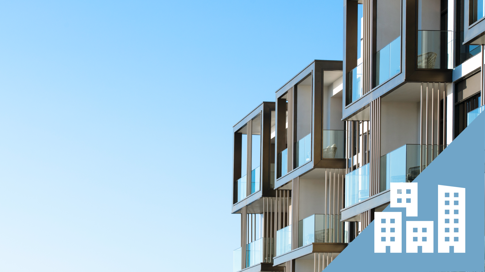 Modern apartment building with glass balconies against a clear blue sky.