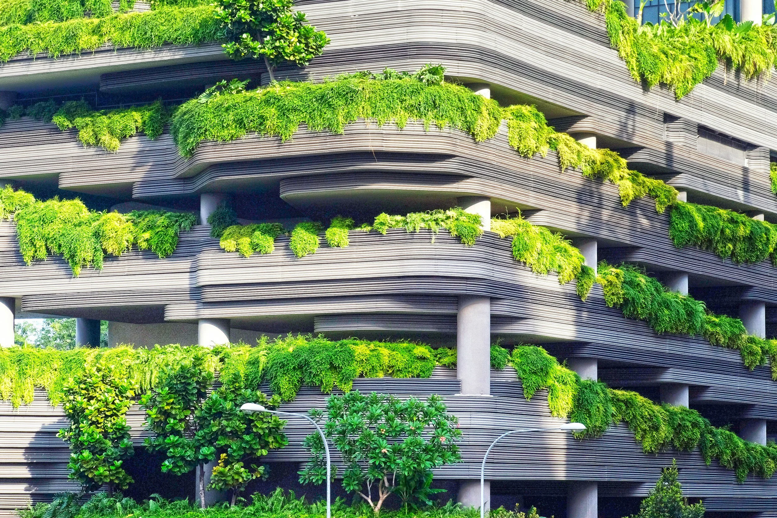 Modern building with multiple level terraces covered in green plants and trees
