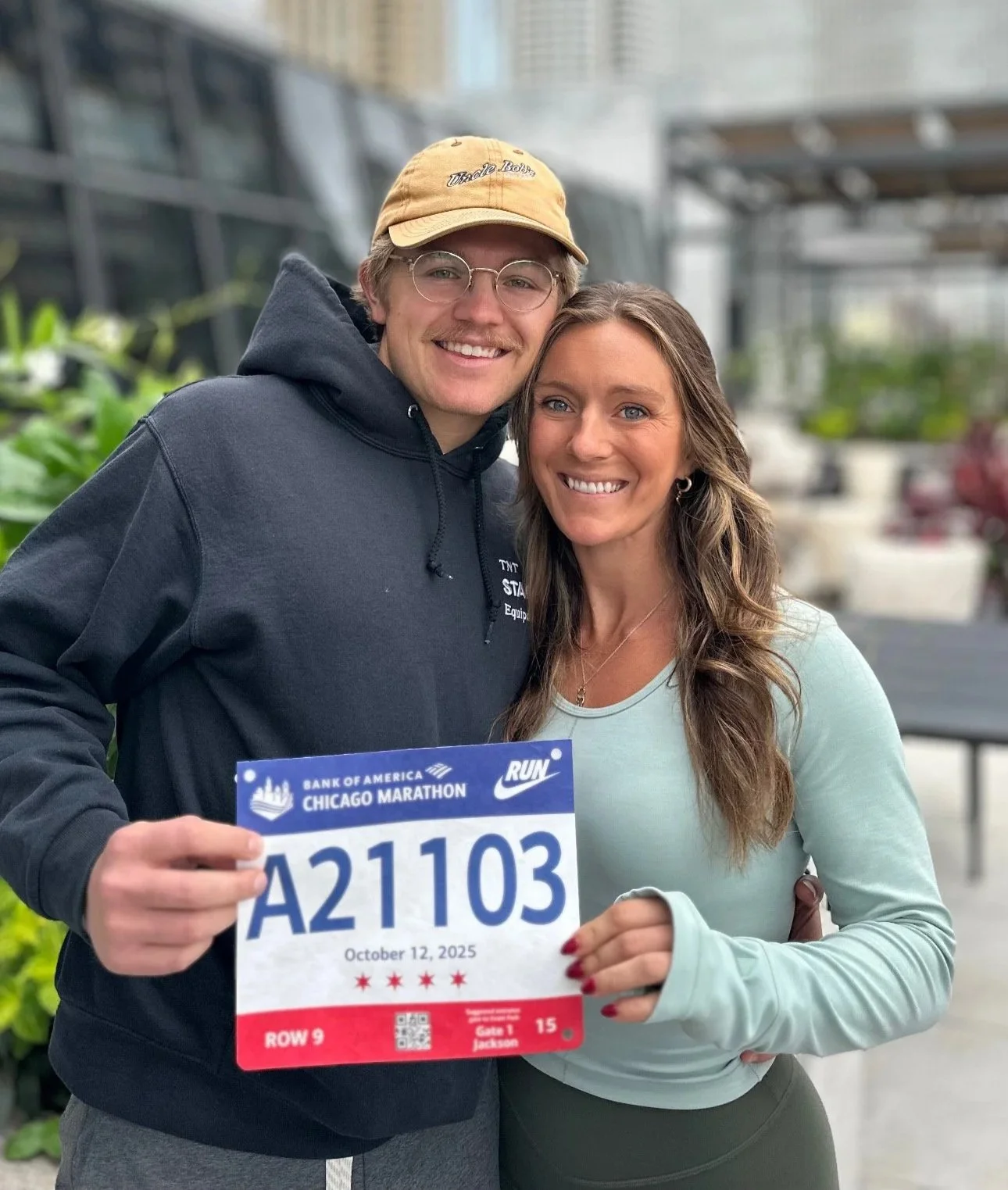 Ryan and Nicole at the Chicago Marathon, holding a race bib with the number A21103, October 12, 2025.