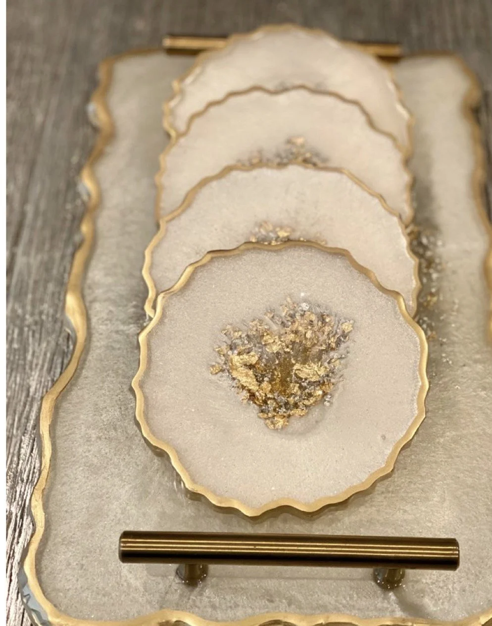 Une décoration de table avec des assiettes rondes et dorées, contenant des cristaux ou des paillettes dorées, sur une surface en bois.