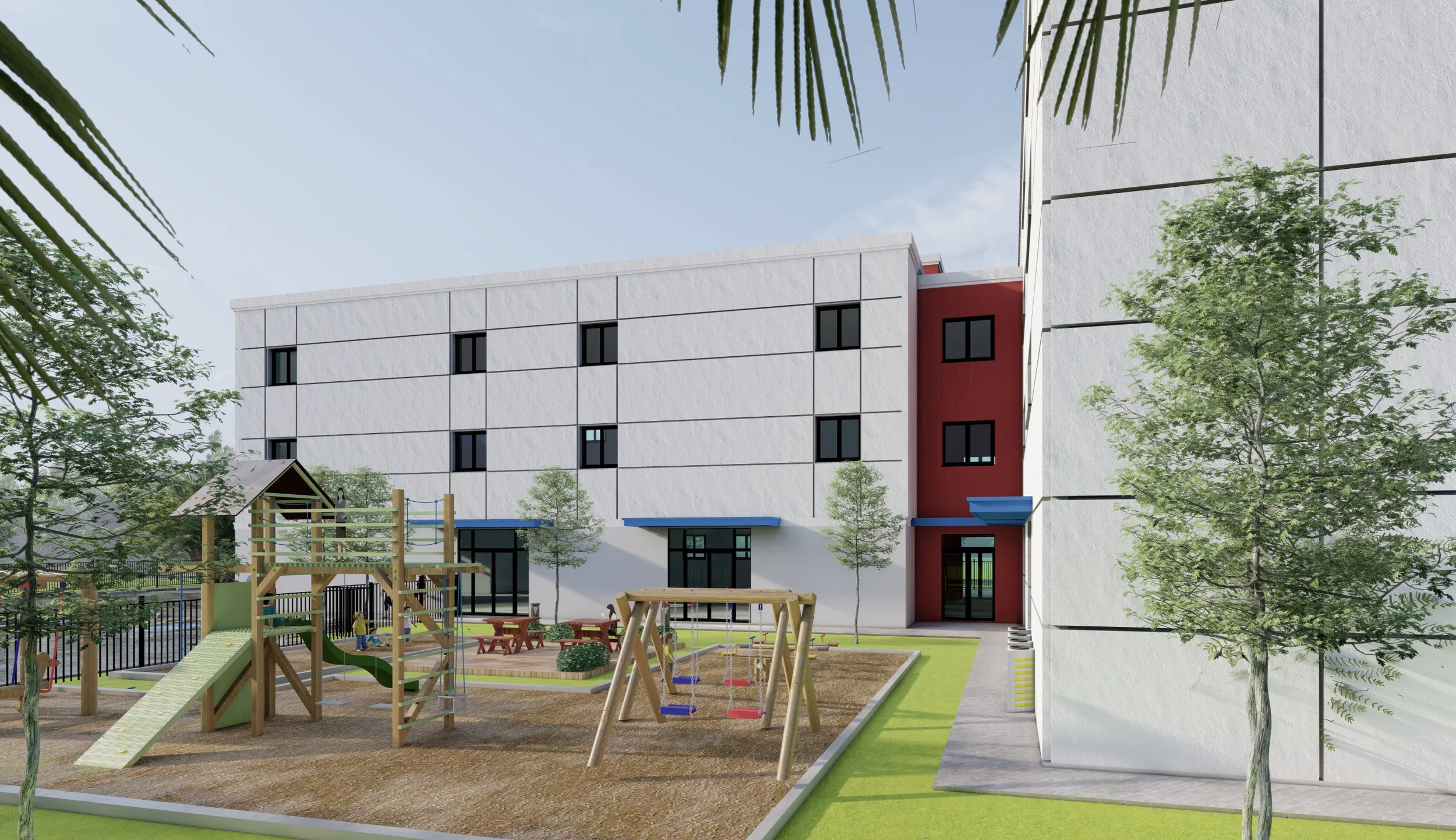 A modern playground area in front of a multi-story white building with black window frames, featuring trees, a toddler slide, swings, and picnic tables, with a clear sky overhead.