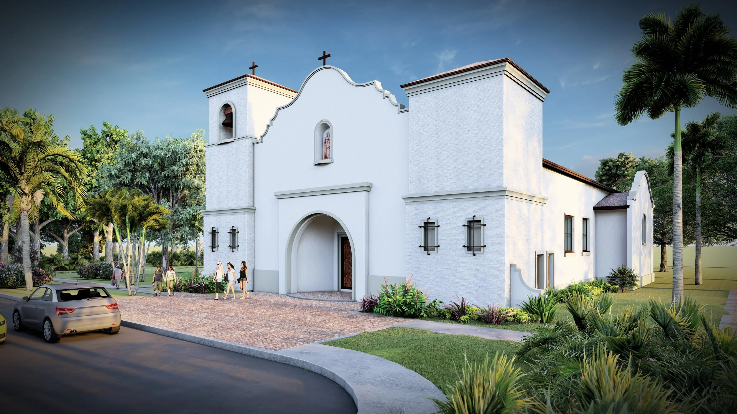 A white church with two crosses on top, arched entrance, and small bell tower, surrounded by green trees and plants, with a brick parking lot in front and people walking nearby.