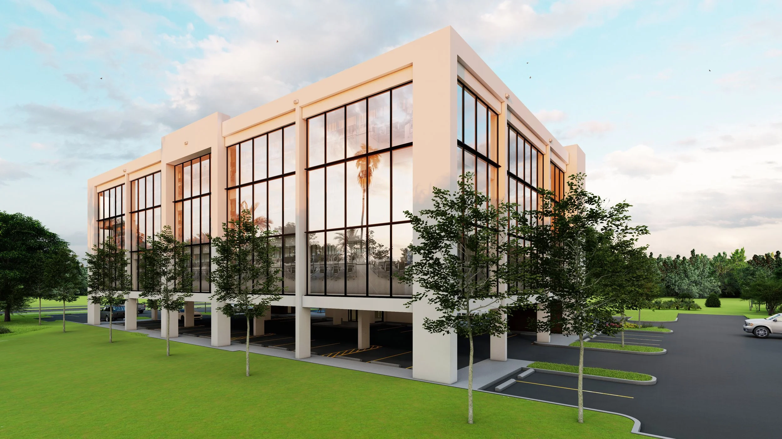 Modern office building with large glass windows, surrounded by green lawn and trees, with parking spaces underneath and a few cars parked in the lot, during daytime with a partly cloudy sky.