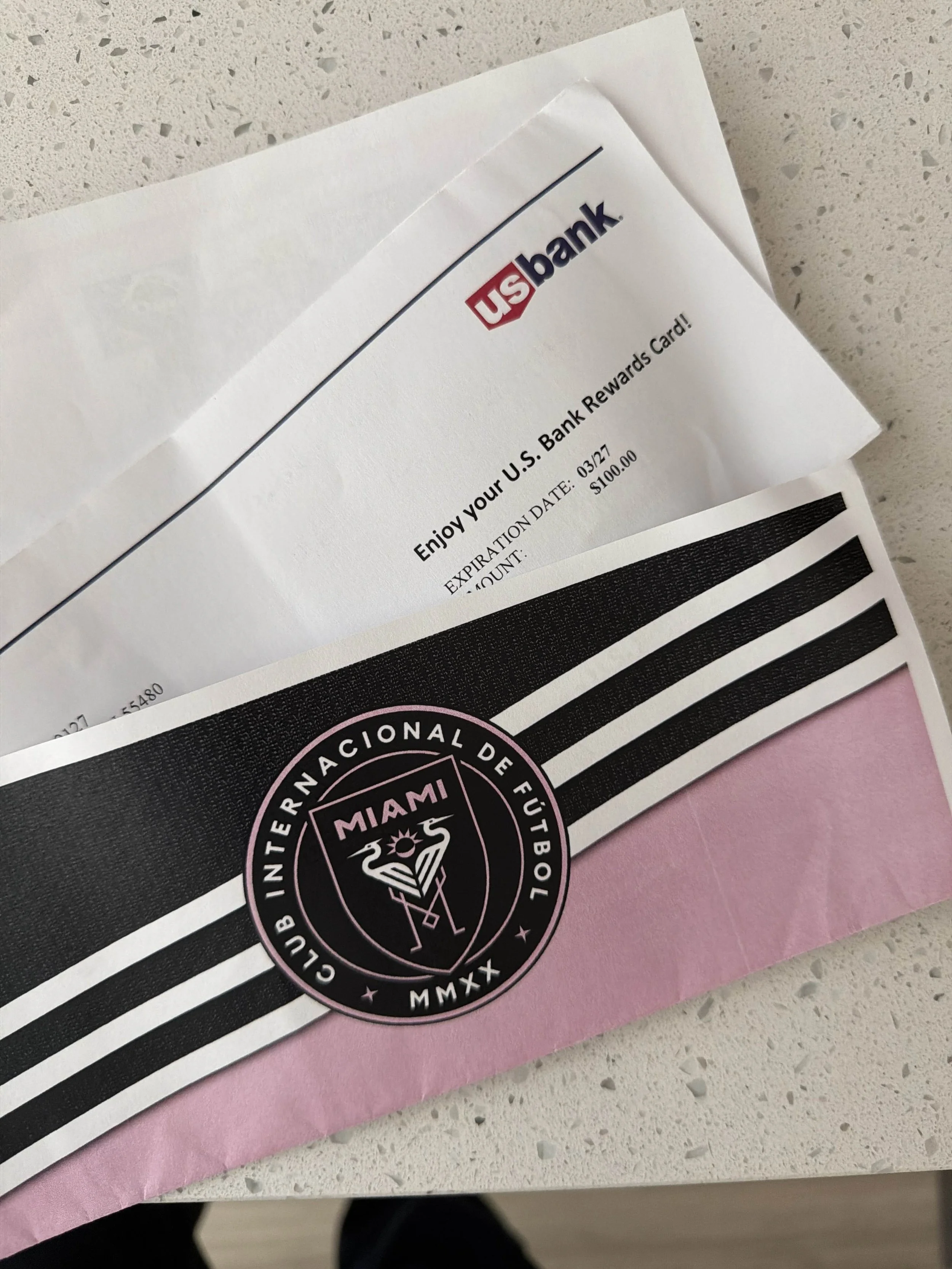 U.S. Bank rewards card and a Miami FC football club envelope on a white speckled surface.