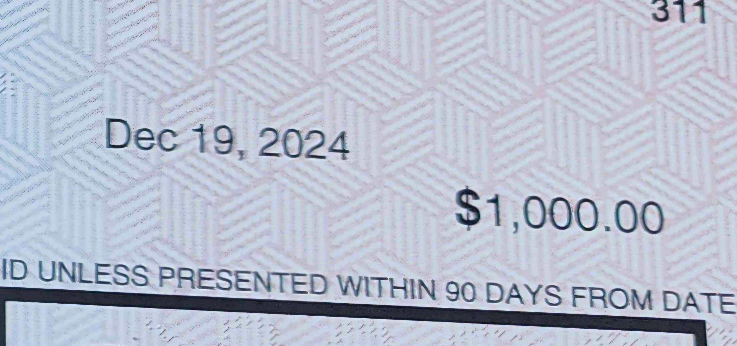 Close-up of a check showing the date December 19, 2024, and the amount of one thousand dollars ($1,000.00).