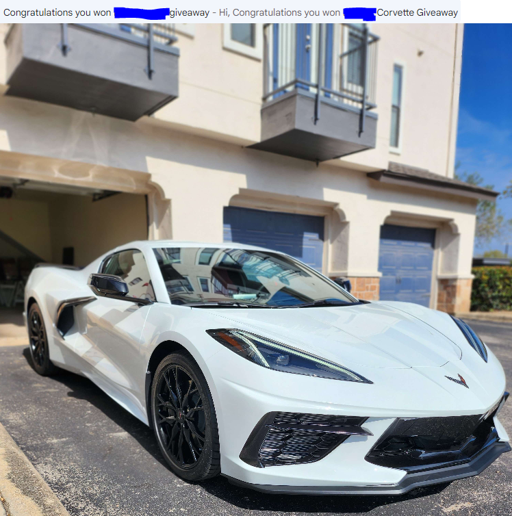 A white Chevrolet Corvette parked in front of an apartment building with blue garage doors and balconies.