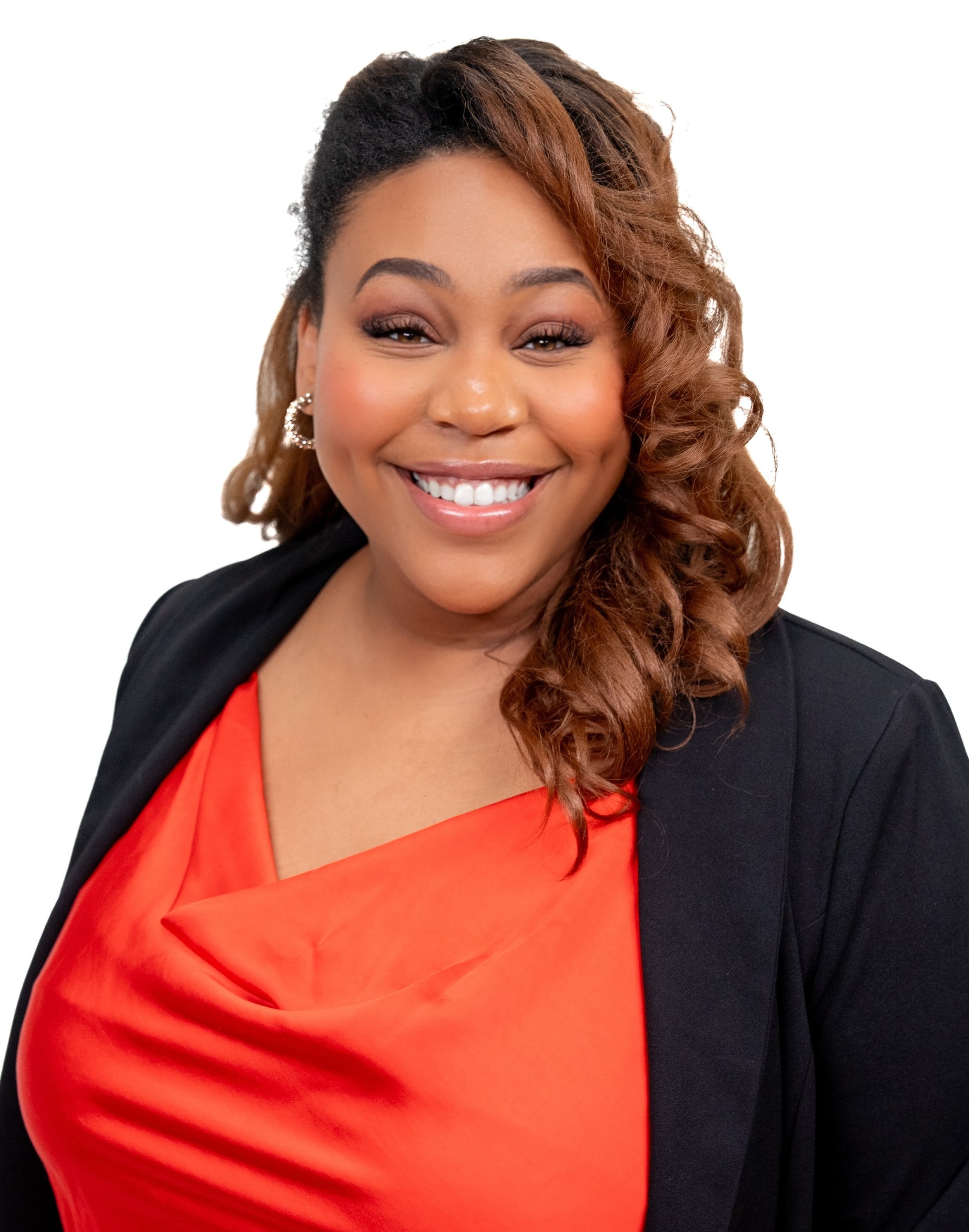 Founder, Malikha Mayes, smiling with curly hair wearing a black blazer and an orange top, against a white background.