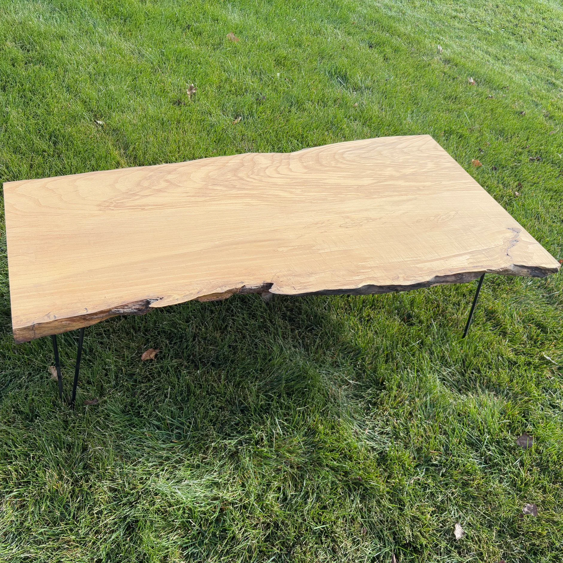 A wooden table outdoors on a grassy lawn.