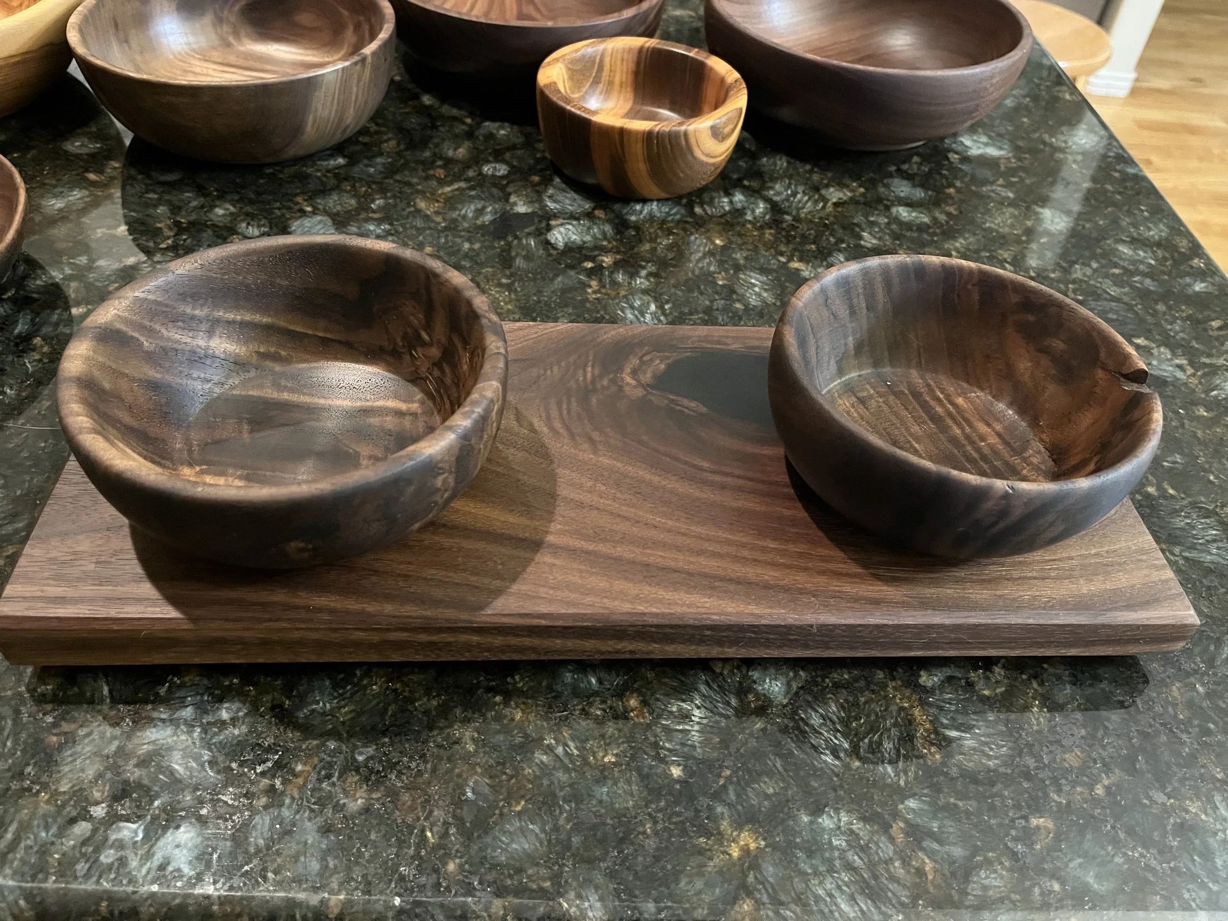 A collection of wooden bowls of various sizes on a marble countertop.