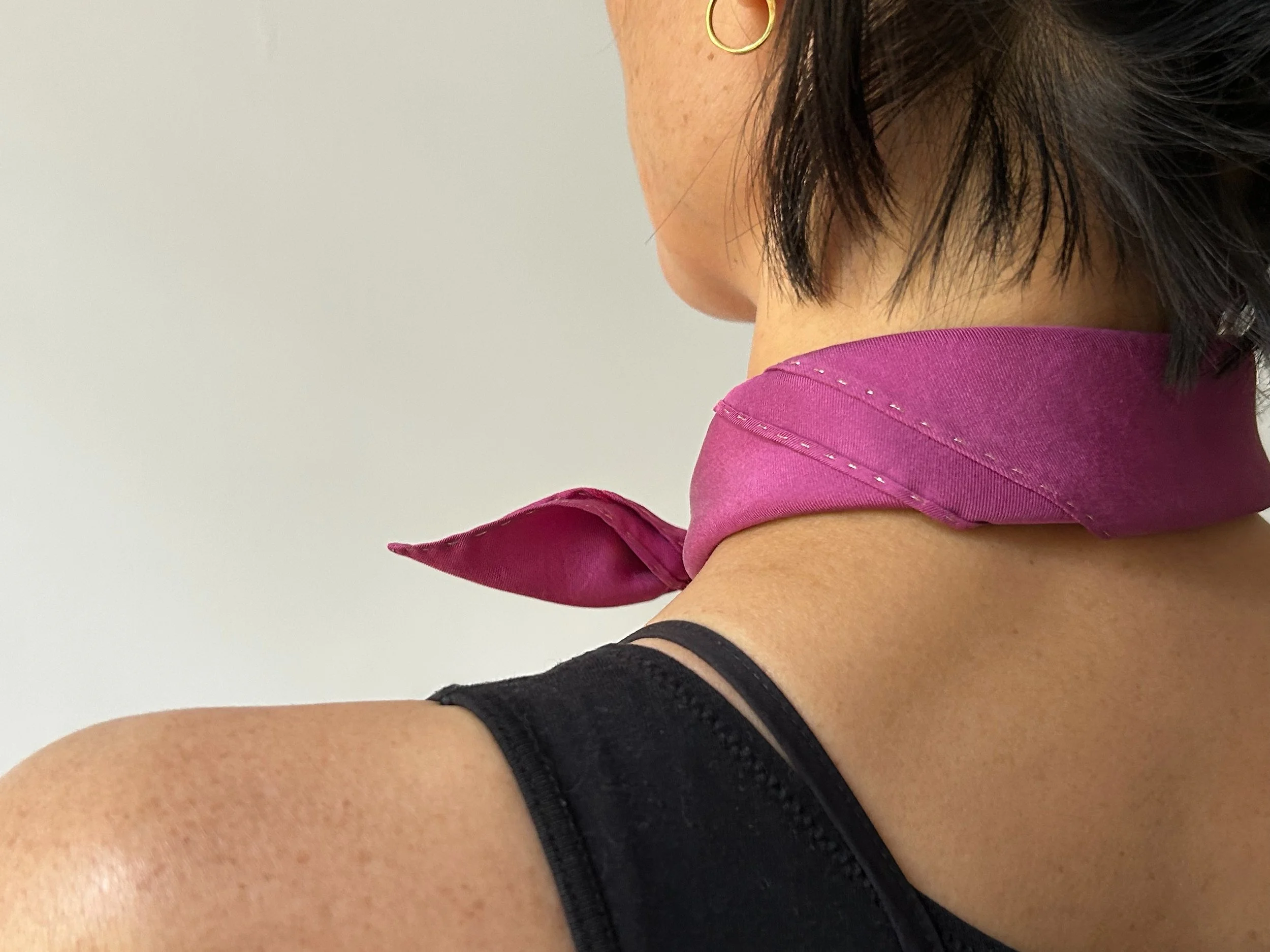 Cochineal silk scarf tied at the neck, back view detail