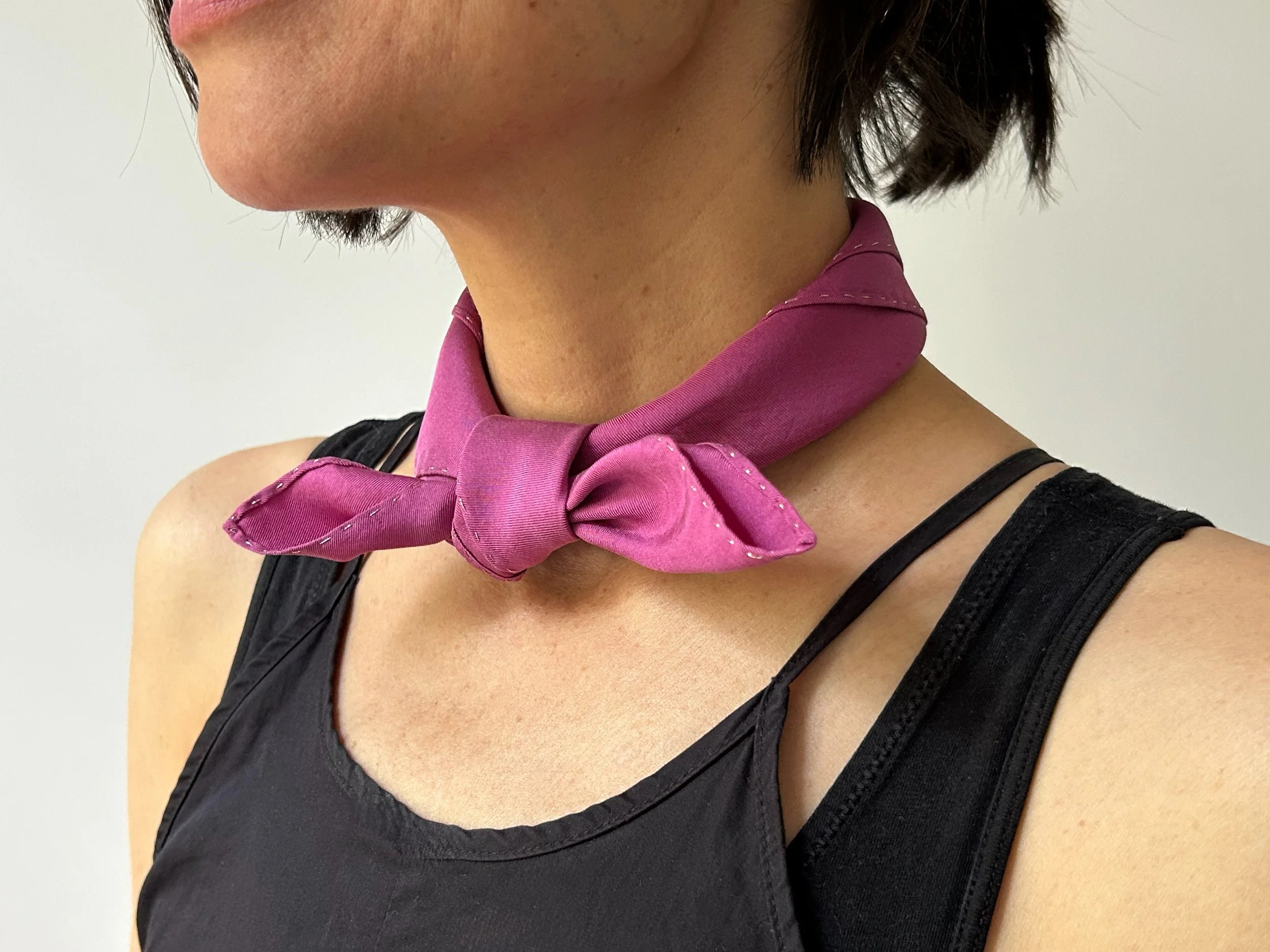 Cochineal silk scarf tied at the neck