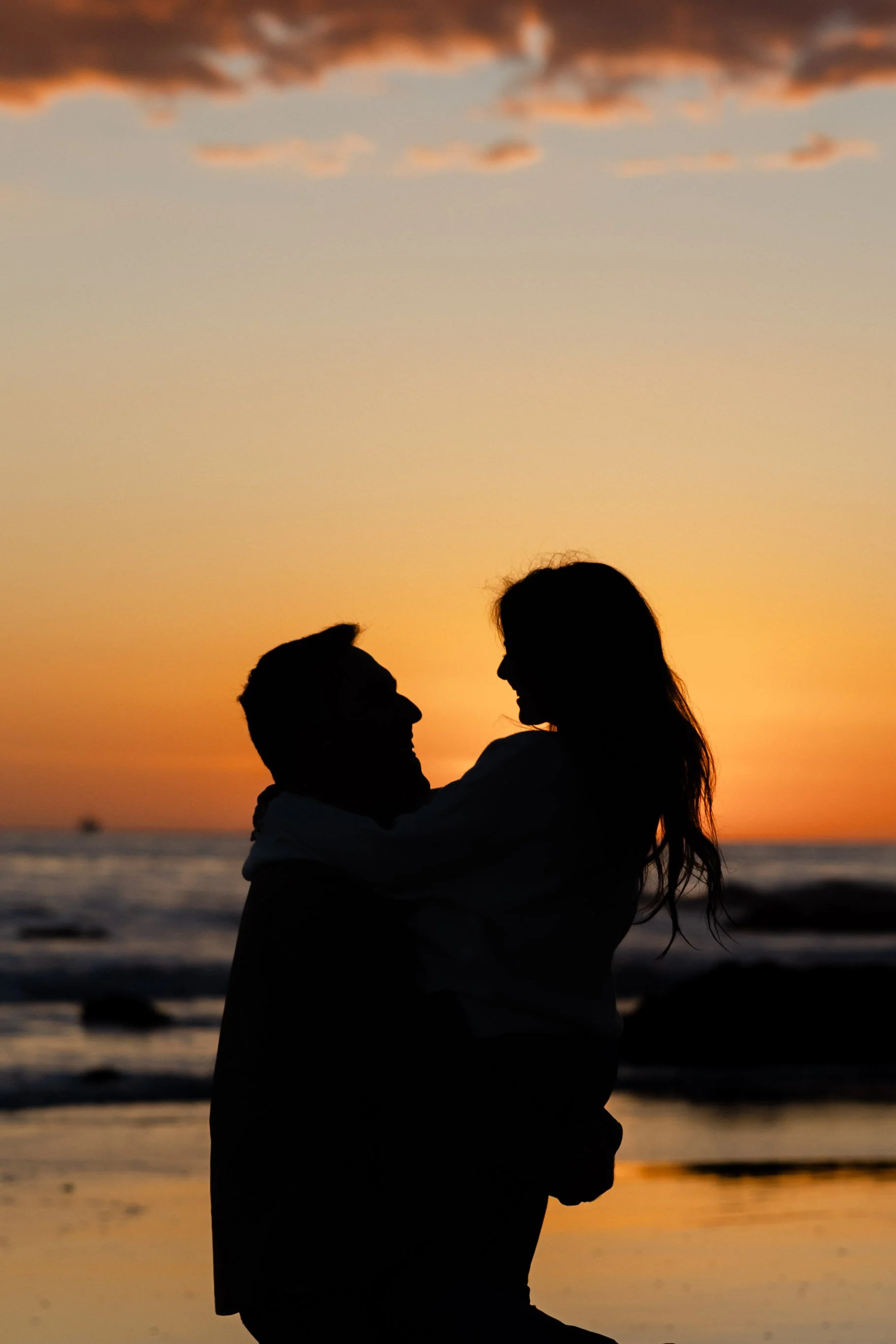 Silhouette of a couple embracing on the beach at sunset