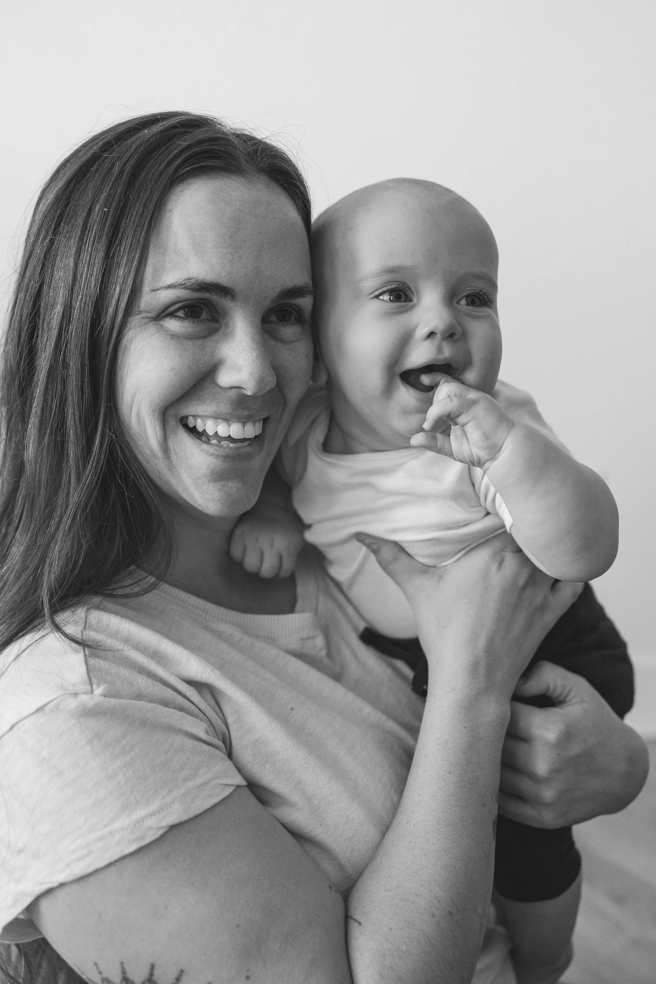 Black and white photo of a smiling woman holding a baby, both looking happy.