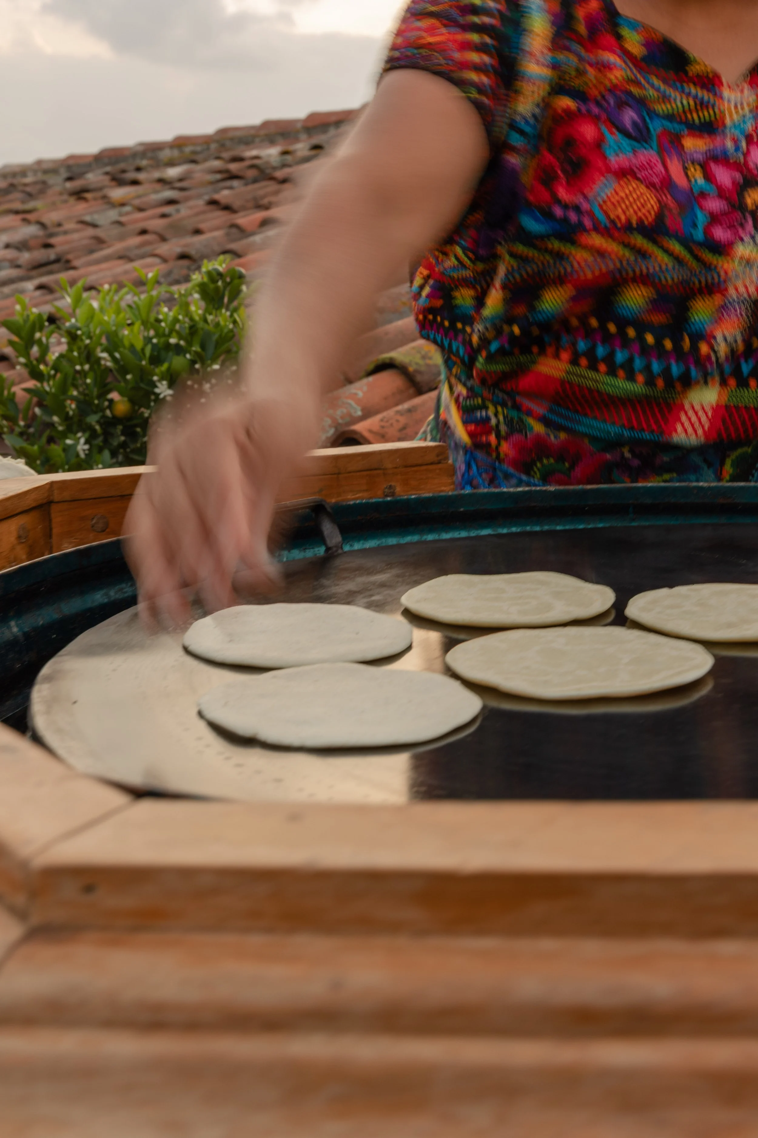 Person cooking traditional Mexican tortillas on a griddle.