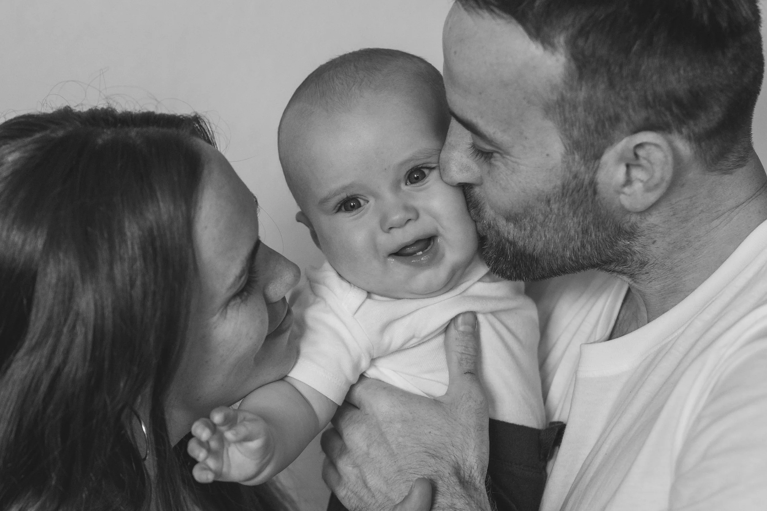 Family of three, mother, father, baby, close-up, black and white.