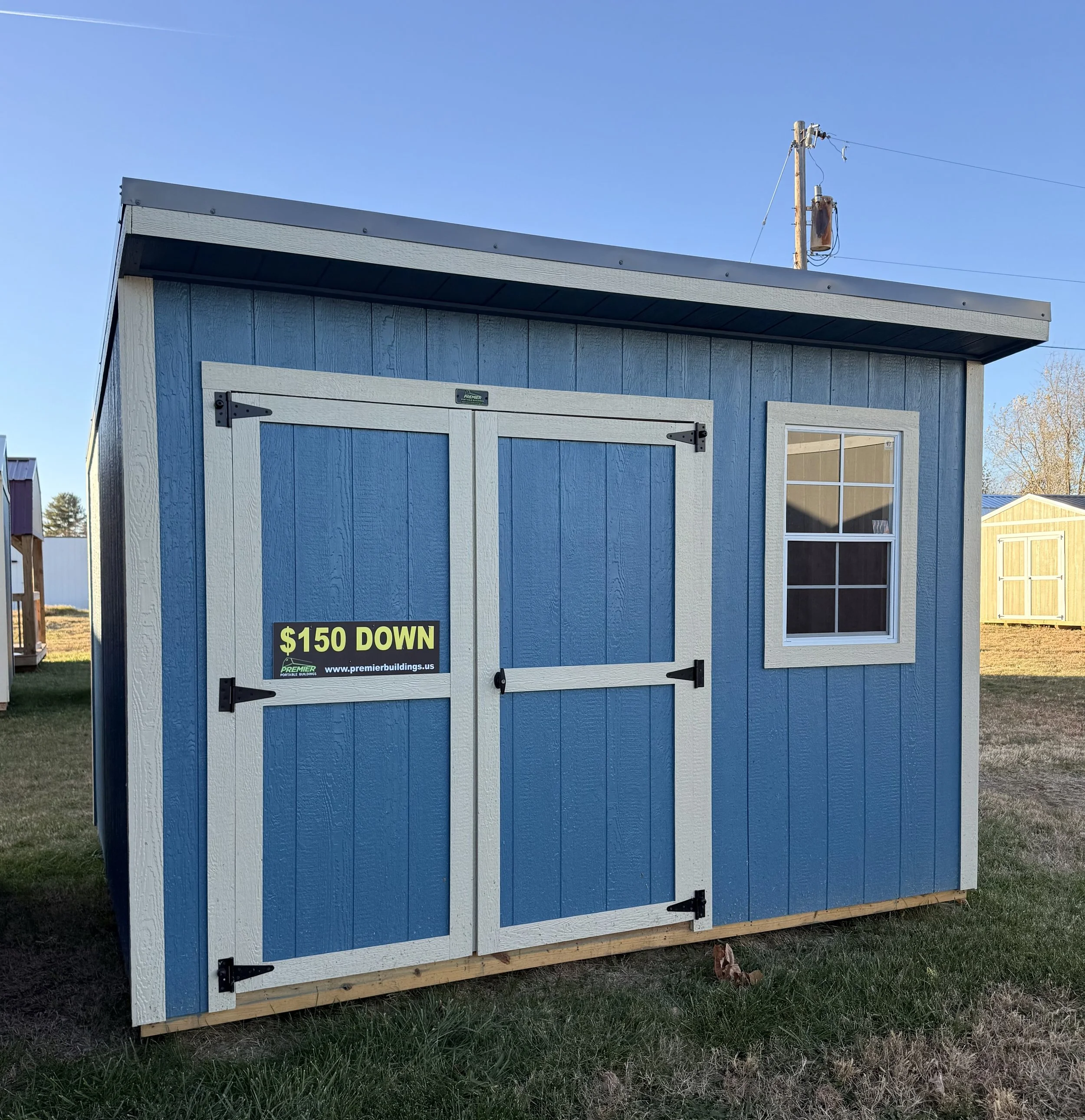 ALT: 10×12 blue cottage-style shed with a front door and window, featuring a charming compact design and light blue exterior.