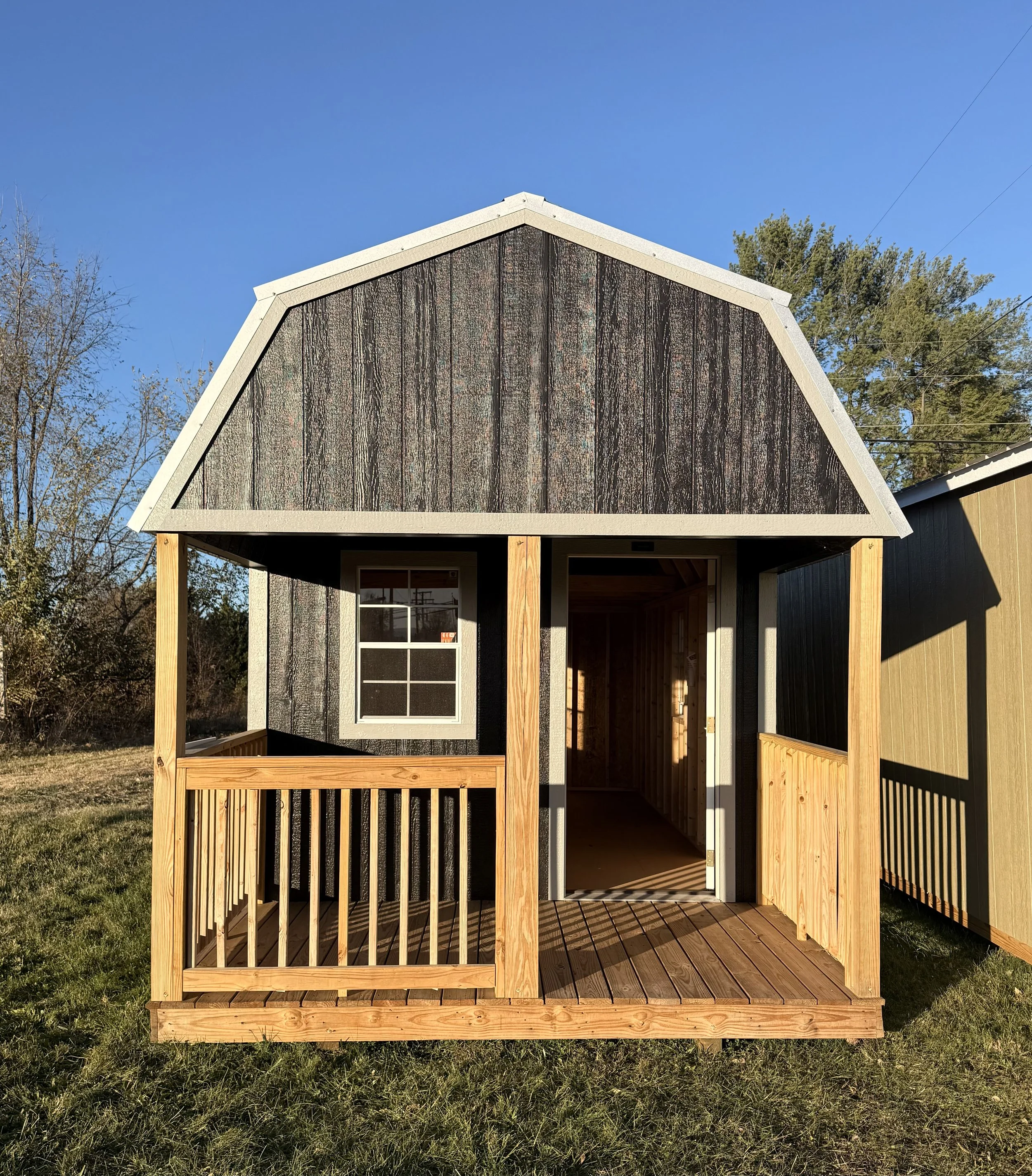 10×24 lofted cabin in an ebony finish with a front porch and upper loft space, showcasing dark exterior siding and a classic cabin design.