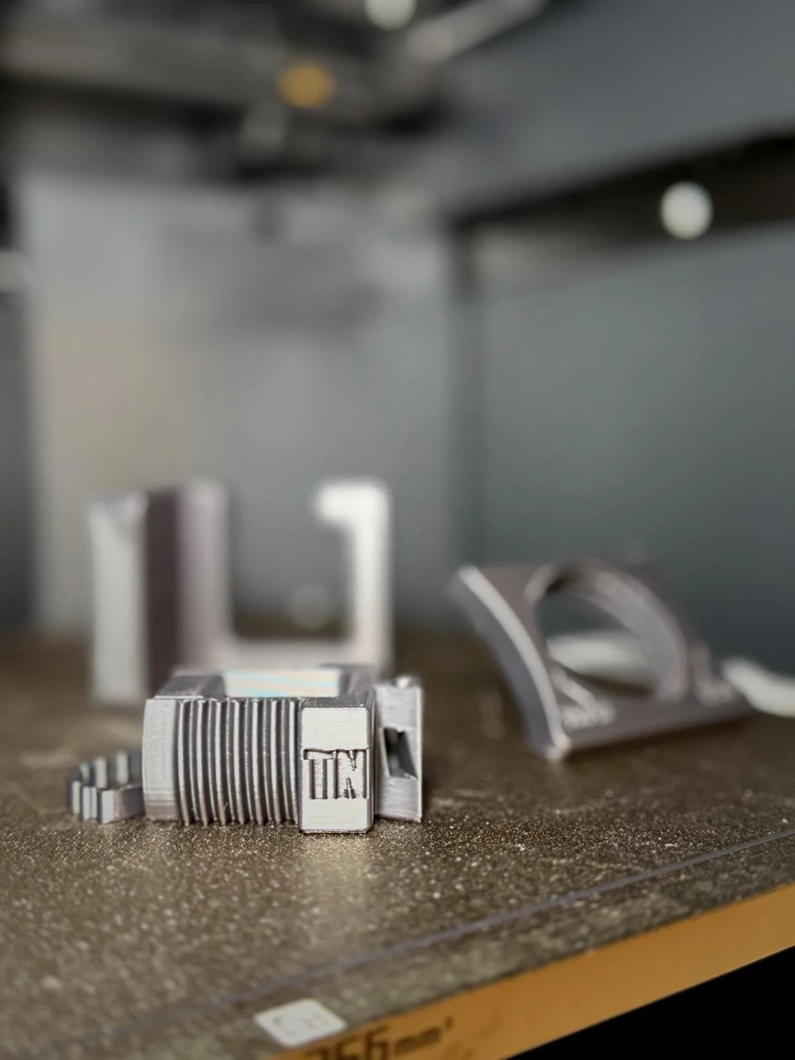 3D-printed TN Works vertical rail hook components sitting on a printer bed, made in Florida for home organization and outdoor fence balcony rail systems.