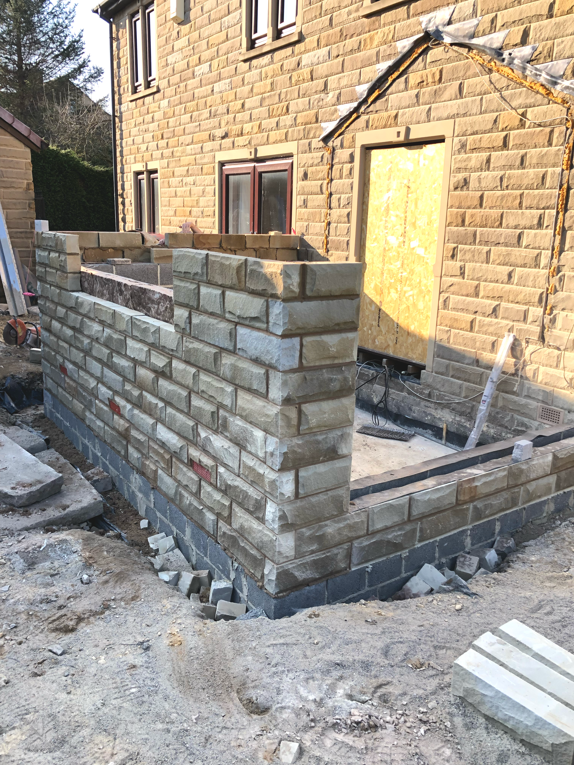 Building under construction with a brick wall and construction tools and materials around it.