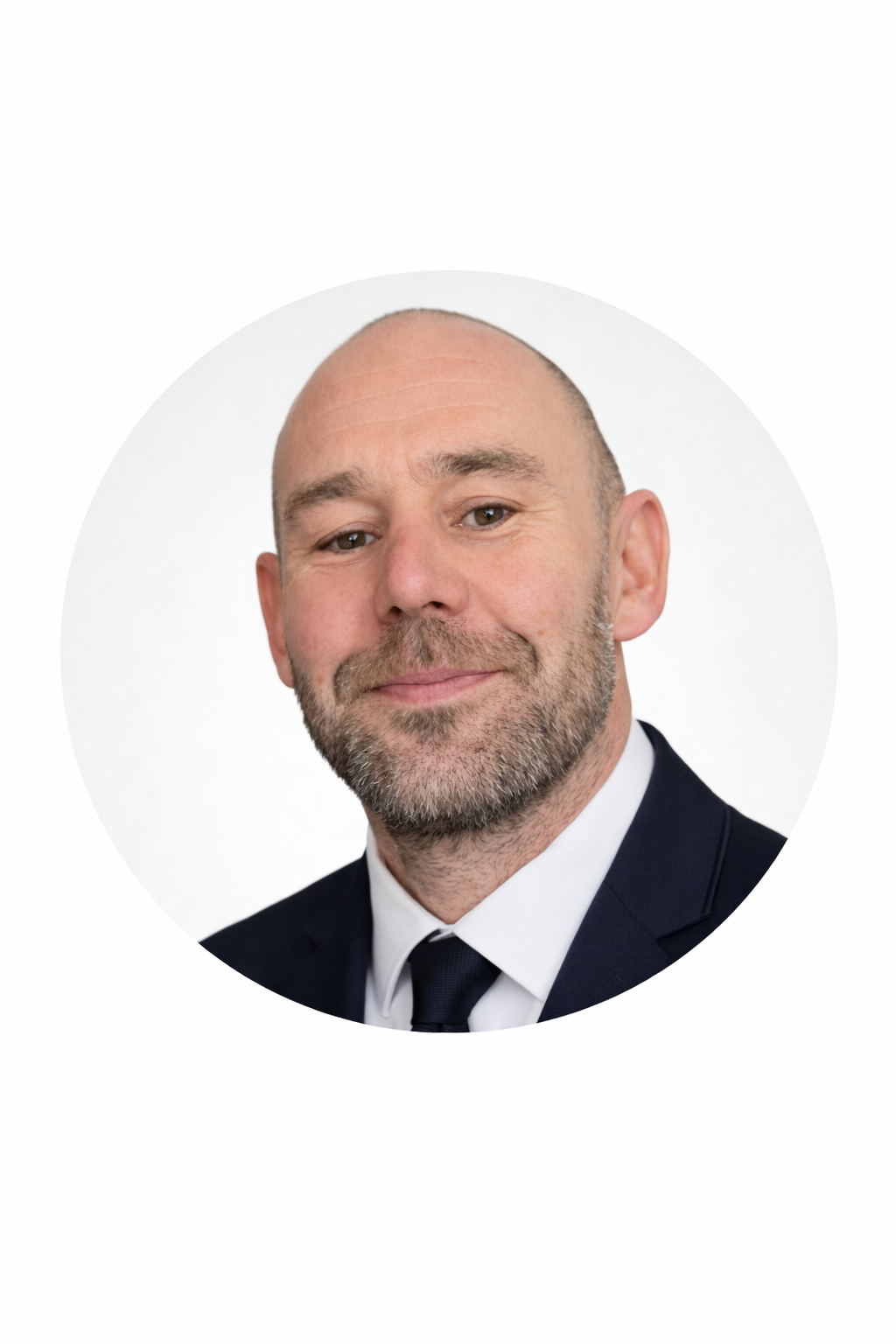Headshot of a middle-aged man with a beard, wearing a dark suit, white shirt, and dark tie, against a white background.