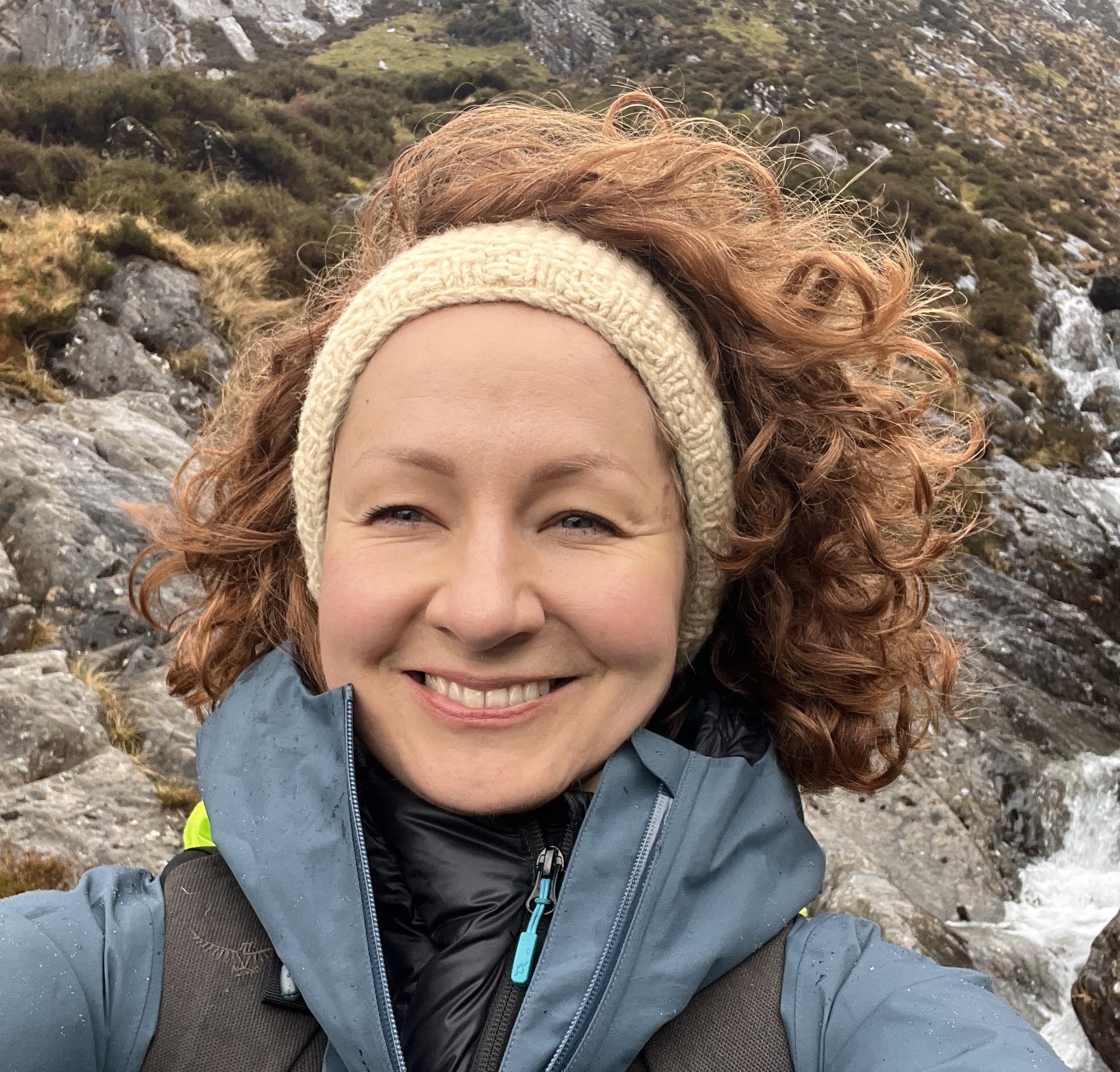 Profile picture of a smiling woman with curly ginger hair