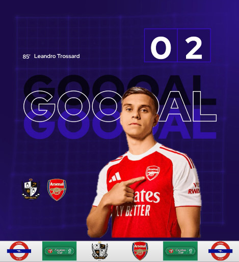 Soccer player Leandro Trossard in Arsenal jersey celebrates goal with a finger point, with a score of 2-0 displayed, celebrating a match victory.