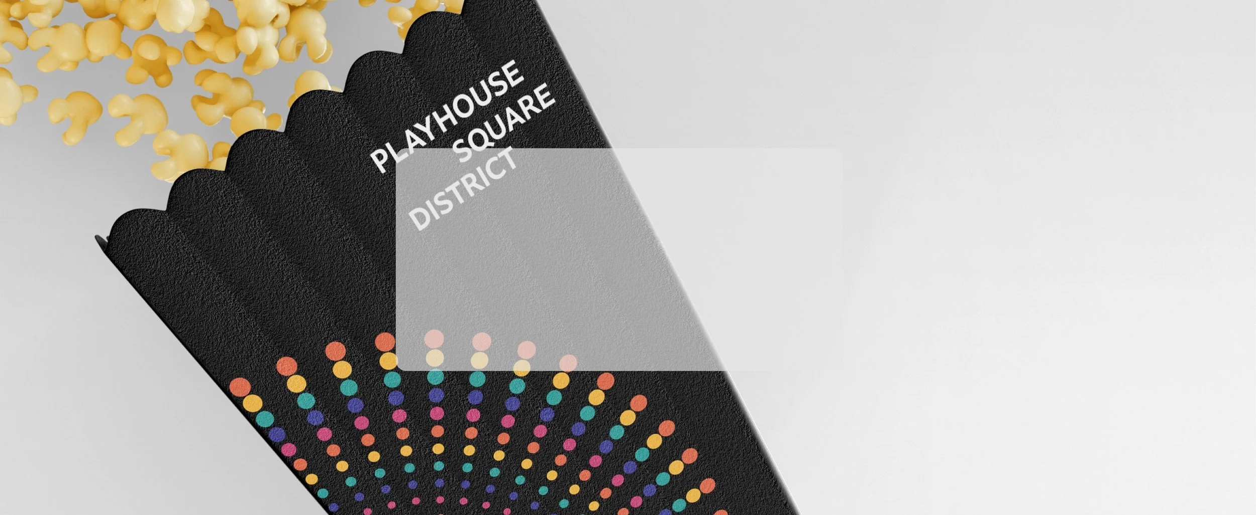 Close-up of a black playhouse-shaped box with multicolored dots on it, labeled with white text reading 'Playhouse Square District.' Some small yellow objects are spilling out of the box.