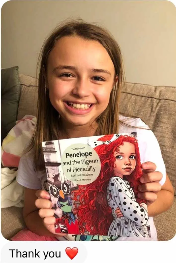 A young girl with long brown hair sitting on a beige couch, smiling and holding a children's book titled 'Penelope and the Pigeon of Piccadilly.' She is wearing a white shirt with colorful patterns. The background includes a beige wall and a couch cu