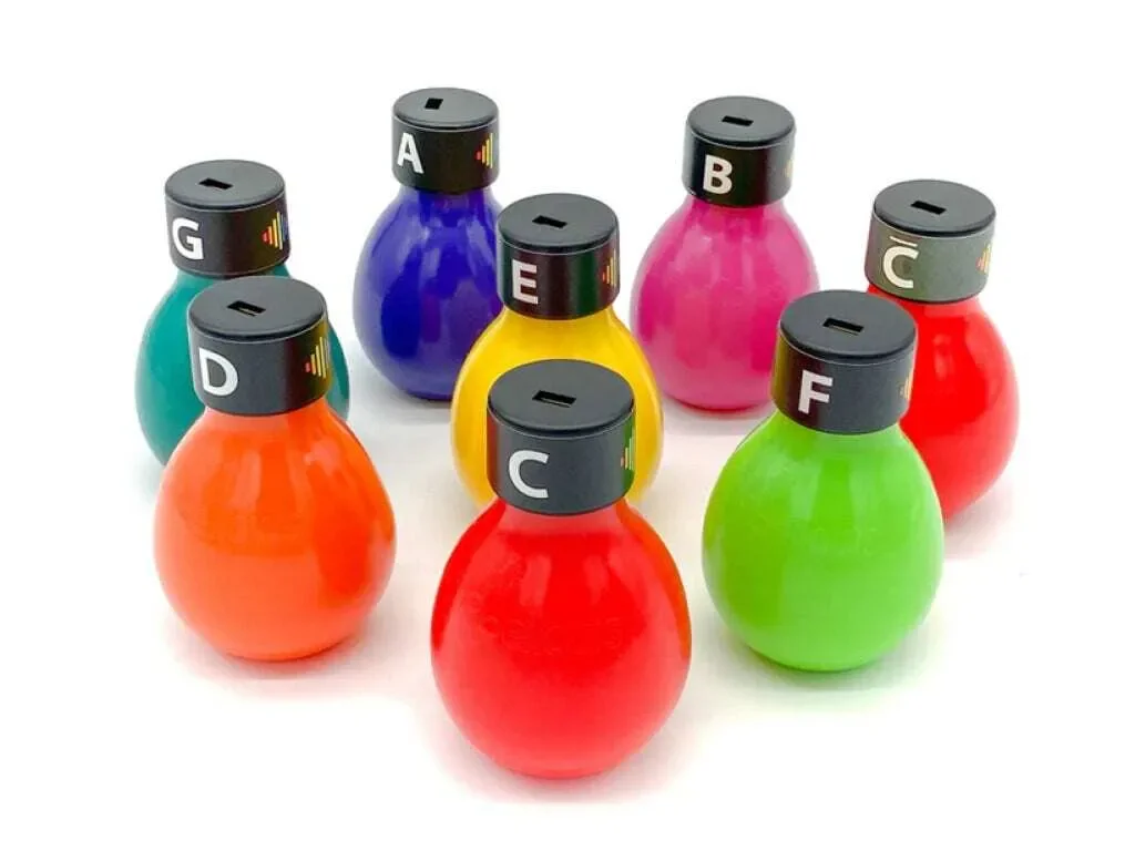 Colorful set of nine bottle-shaped objects with black caps labeled with letters from A to G, arranged on a white surface.