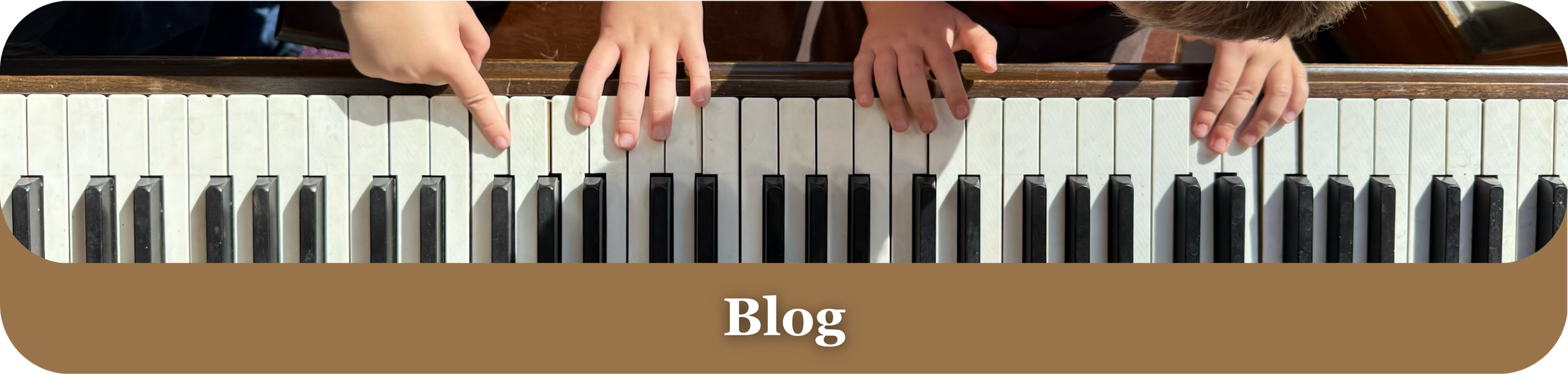Overhead view of two children playing a piano, with their small hands on the keys. A brown banner at the bottom has white text that says 'Blog'.