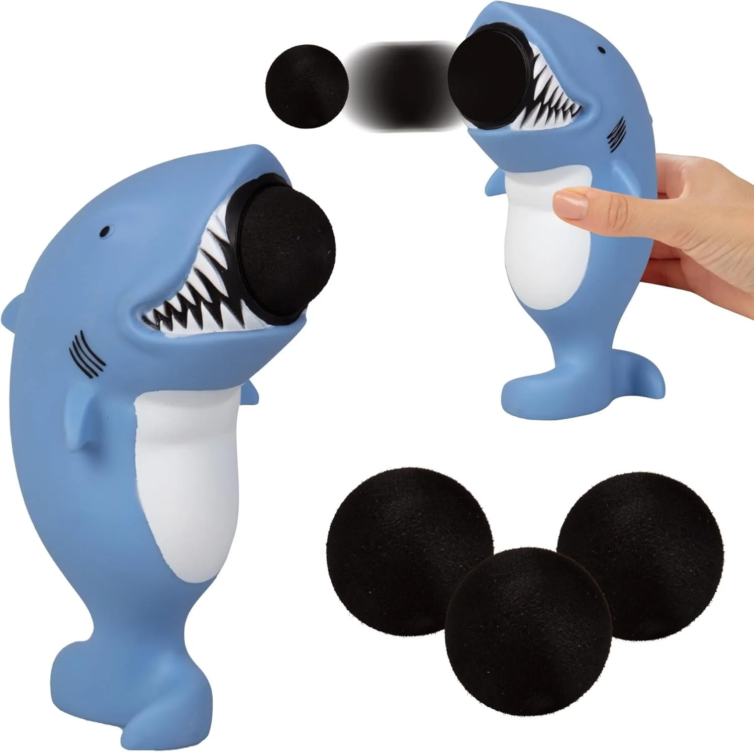 Two blue toy shark ball poppers with black foam balls and a hand squeezing one of the poppers.