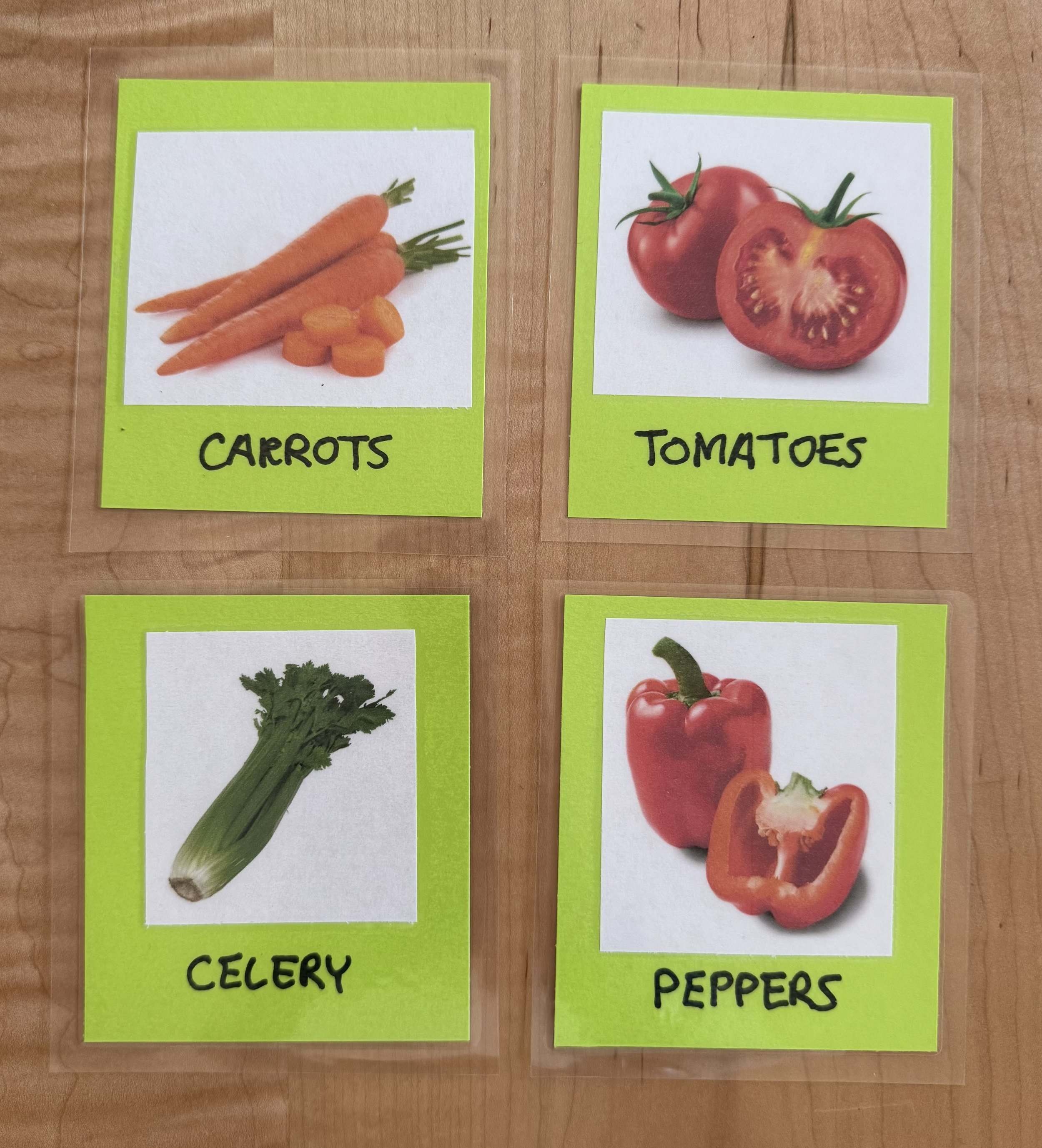 Four choice cards lay on a wooden tabletop. The images and corresponding labels are for carrots, tomatoes, celery and peppers. The background card color is neon green.
