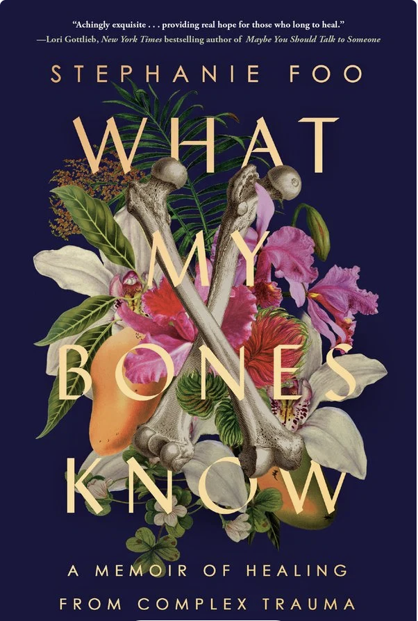 Book cover for 'What My Bones Know' by Stephanie Foo. The cover features a dark blue background with floral illustrations and a pair of crossed skeleton bones in the center. The flowers are various colors including pink, white, and yellow, with green leaves.