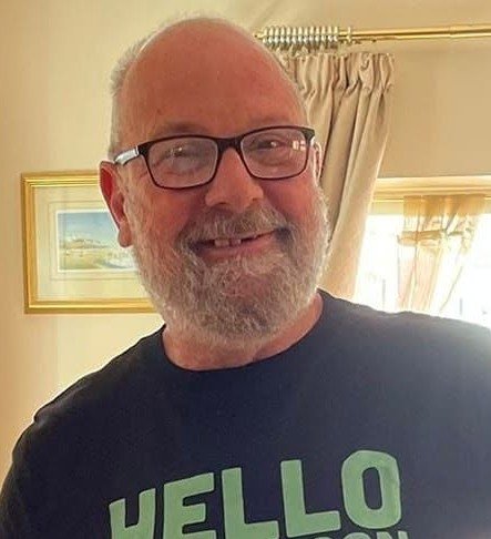 Ed wearing spectacles smiling in a room lit with sunlight