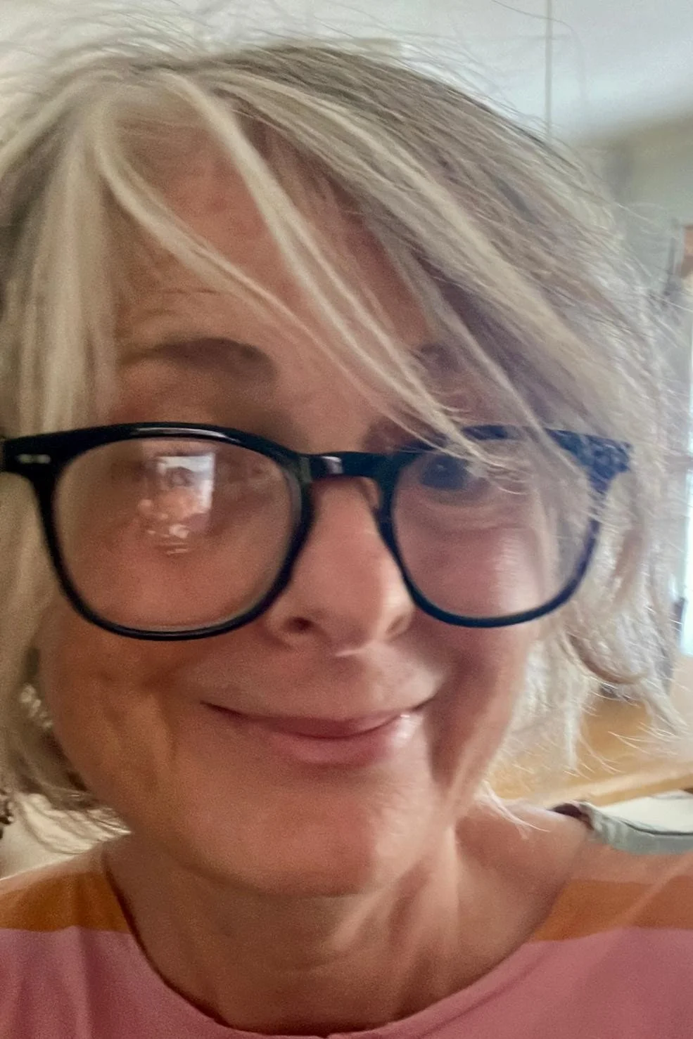 A woman's face. She is smiling and wearing spectacles.