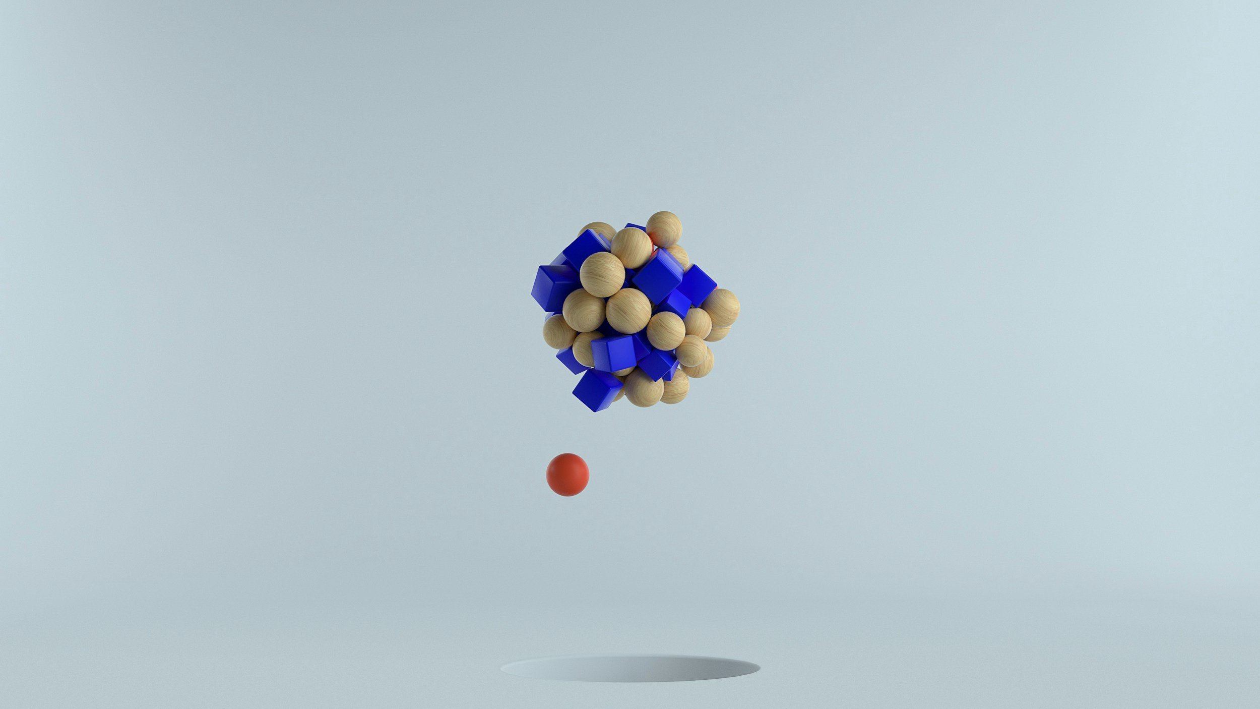 A floating abstract sculpture made of wooden spheres and blue geometric shapes, with an orange sphere below and cast shadow on light gray background.