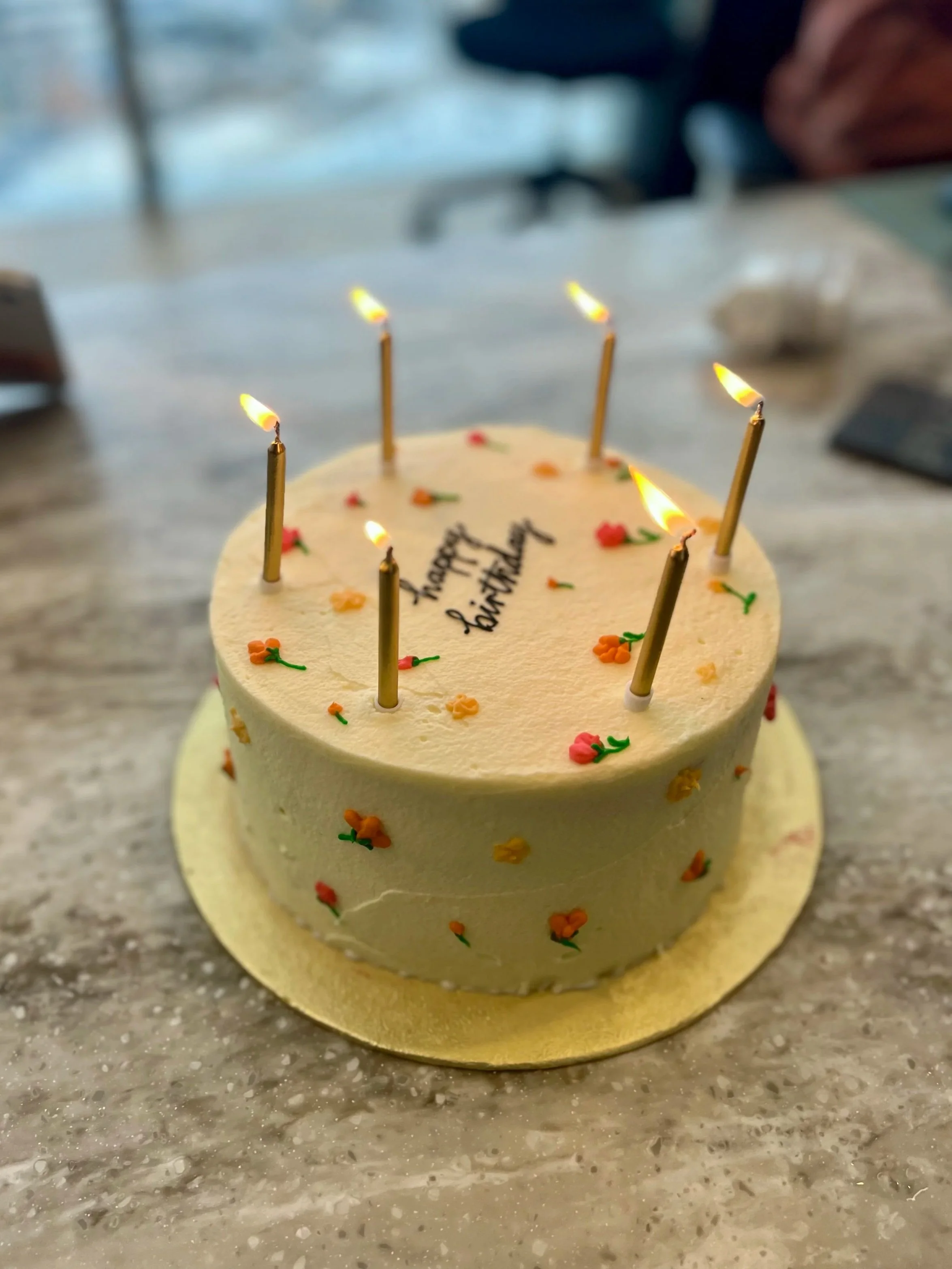 A birthday cake with lit candles and colorful decorations, with a birthday message written on top.