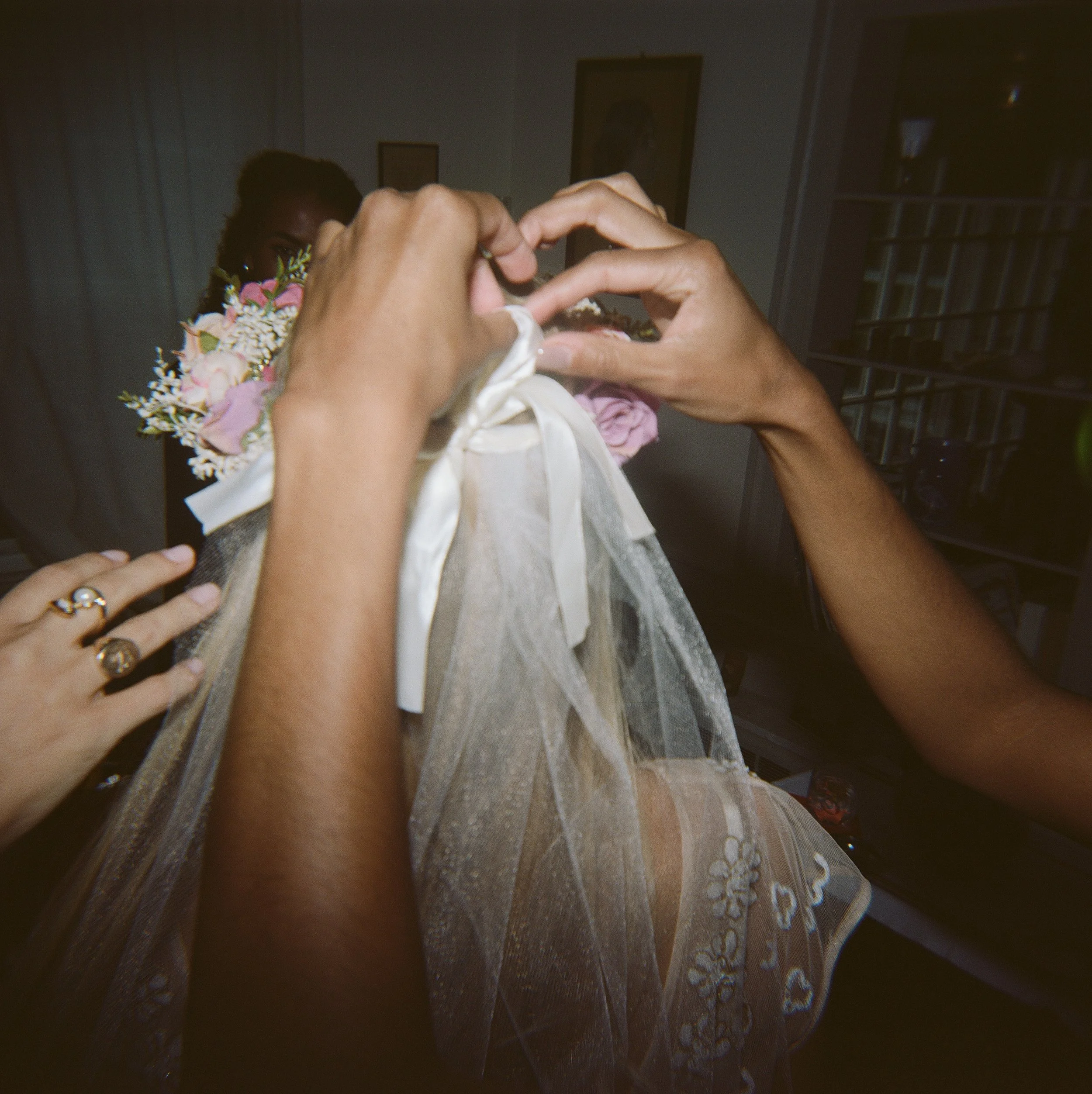 A romantic bridal portrait of a bride adjusting her wedding veil, captured on film with soft natural light and timeless editorial styling. Fine-art wedding photography preserving the quiet, intimate getting-ready moments with a nostalgic, documentary