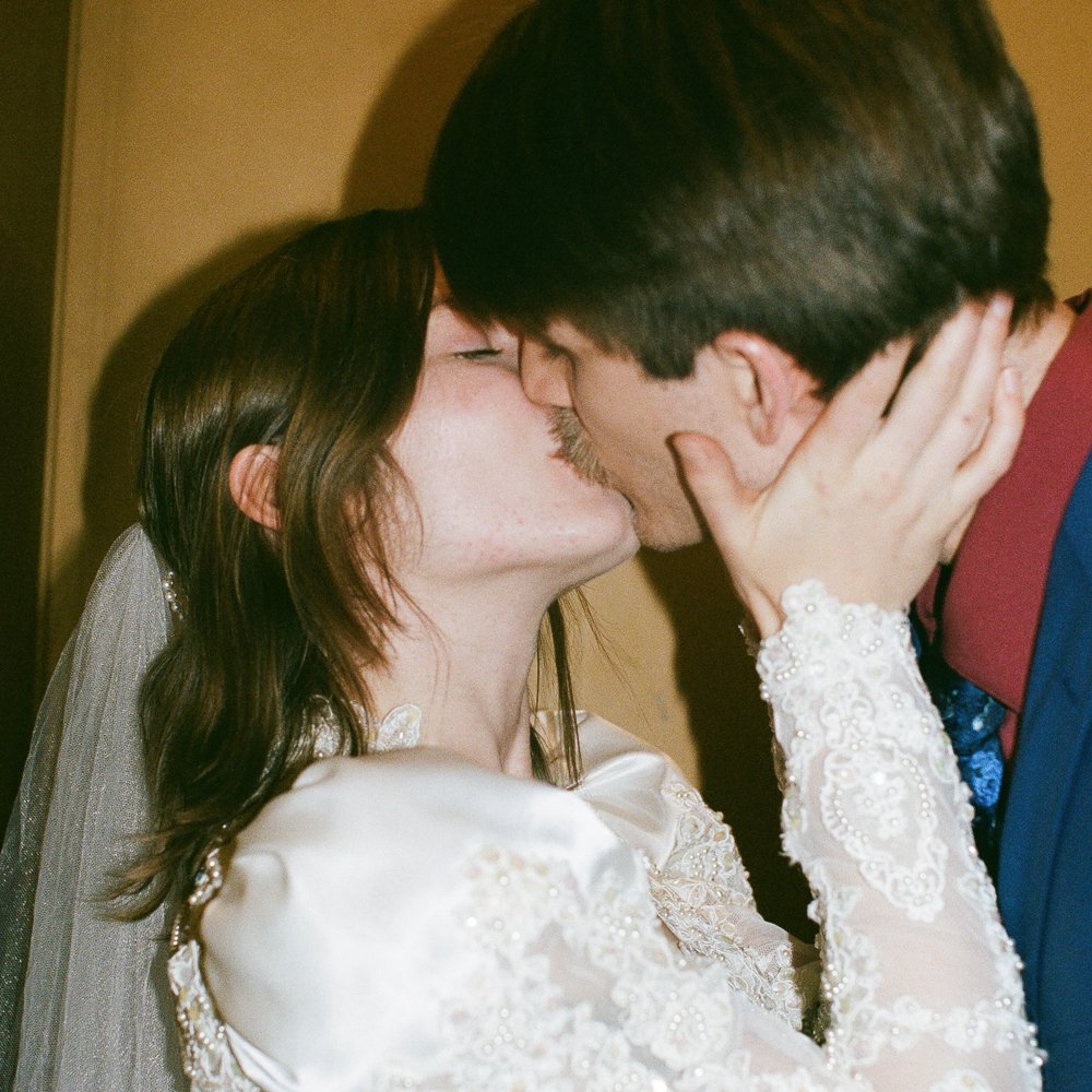 Young couple in wedding attire kissing in an elevator