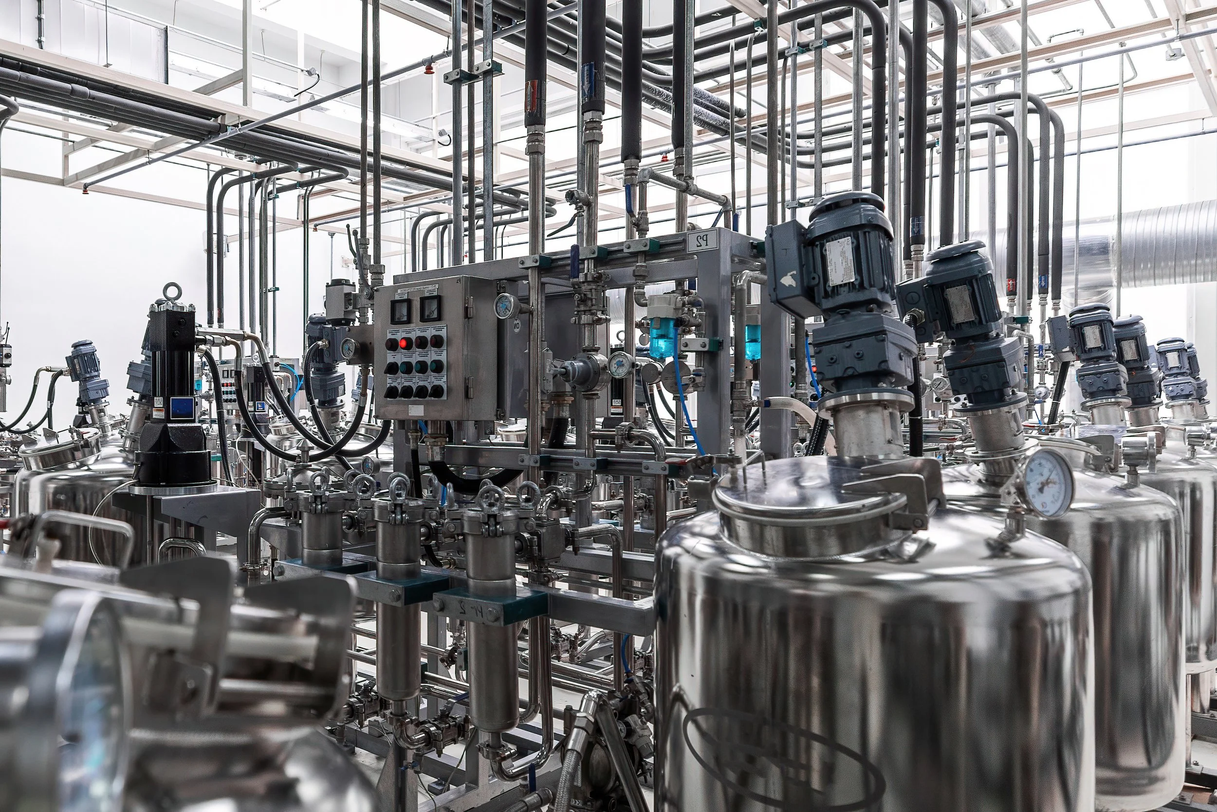 Industrial equipment with pipes, tanks, and gauges in a factory or processing plant.